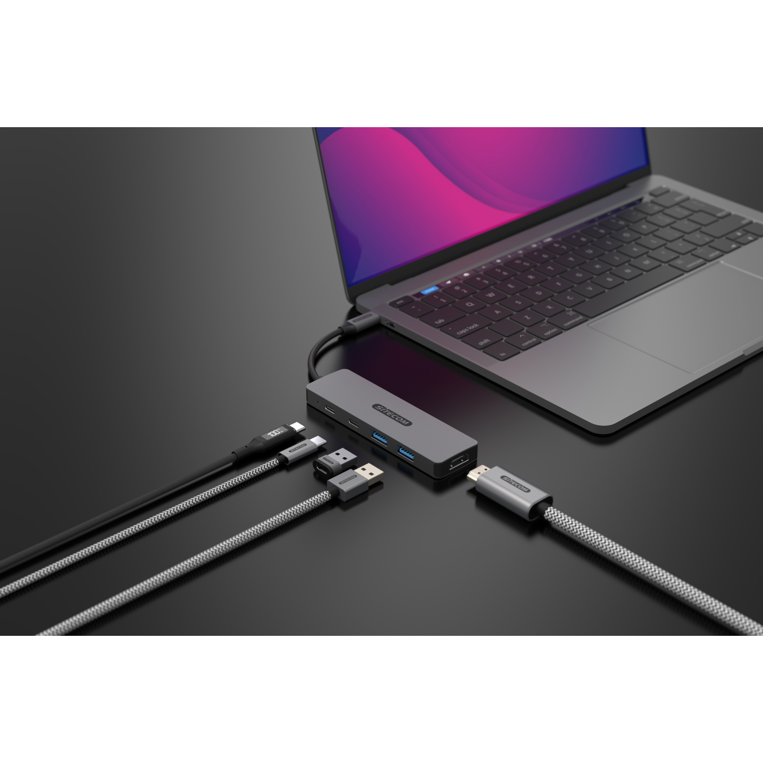 Ein Laptop, der über ein Hub mit verschiedenen Kabeln verbunden ist, auf schwarzem Grund.
