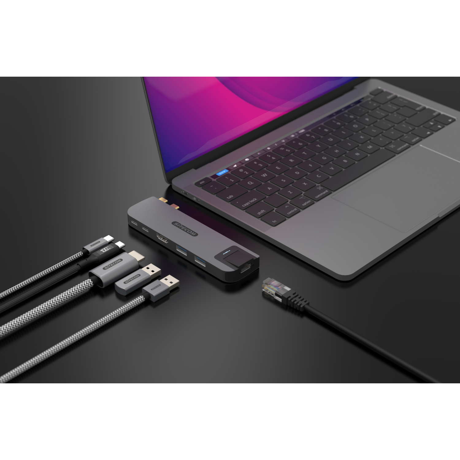 Ein Laptop, der mit einem Hub mit Kabeln auf einer dunklen Oberfläche verbunden ist.