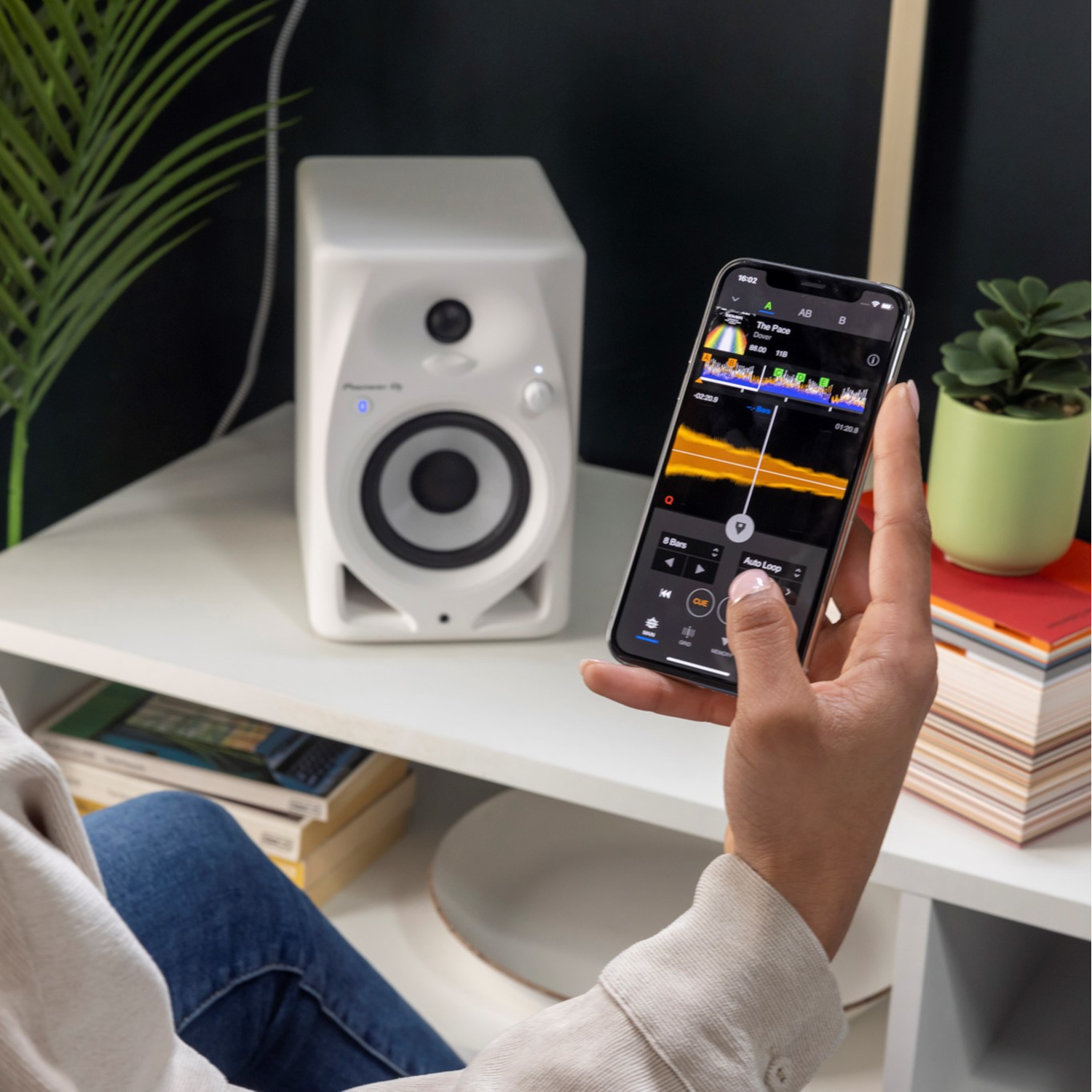 Een persoon houdt een telefoon vast met audio-instellingen. Links is een witte luidspreker.