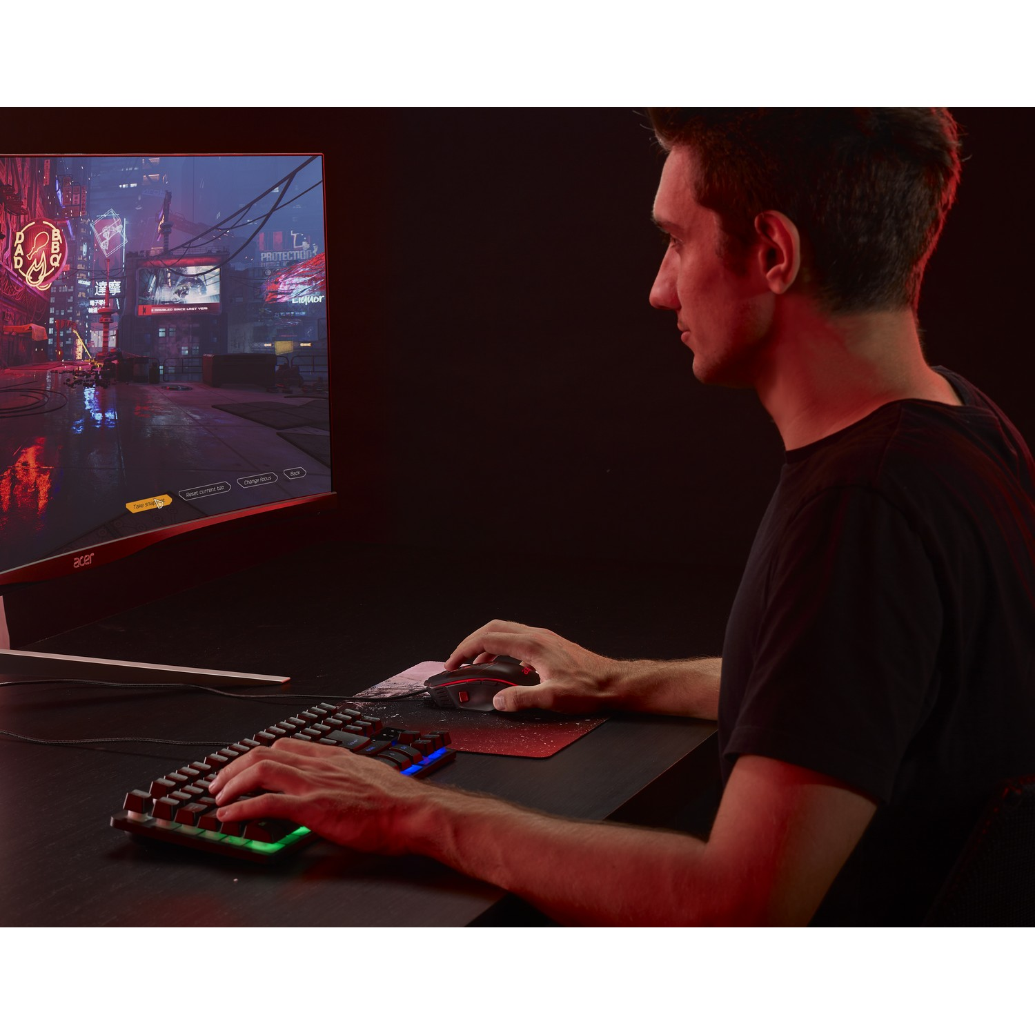 Un uomo gioca su un computer con un monitor curvo. Usa un mouse e una tastiera su una scrivania scura.