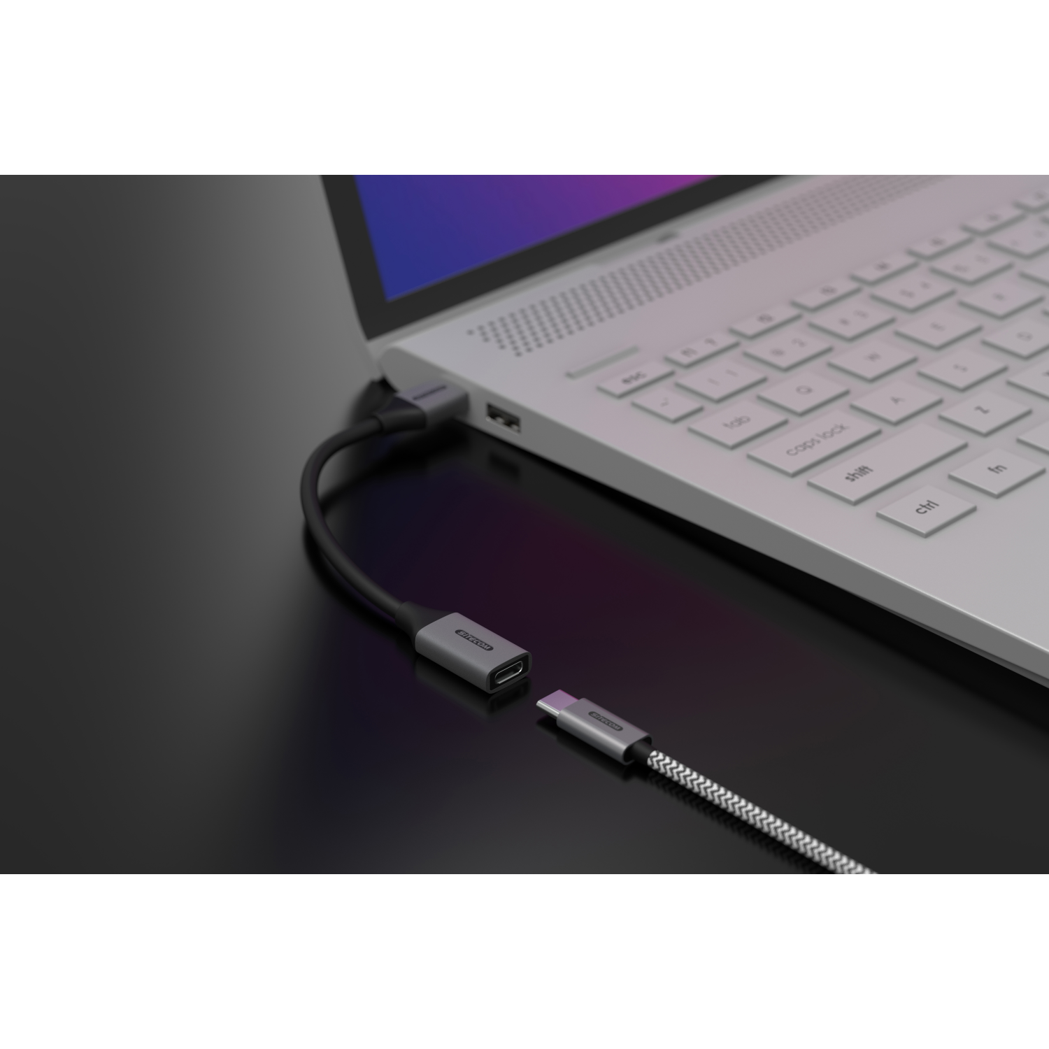 Ein Laptop mit einem angeschlossenen grauen Adapter. Adapter hat einen USB-C-Anschluss und ein schwarzes Kabel.