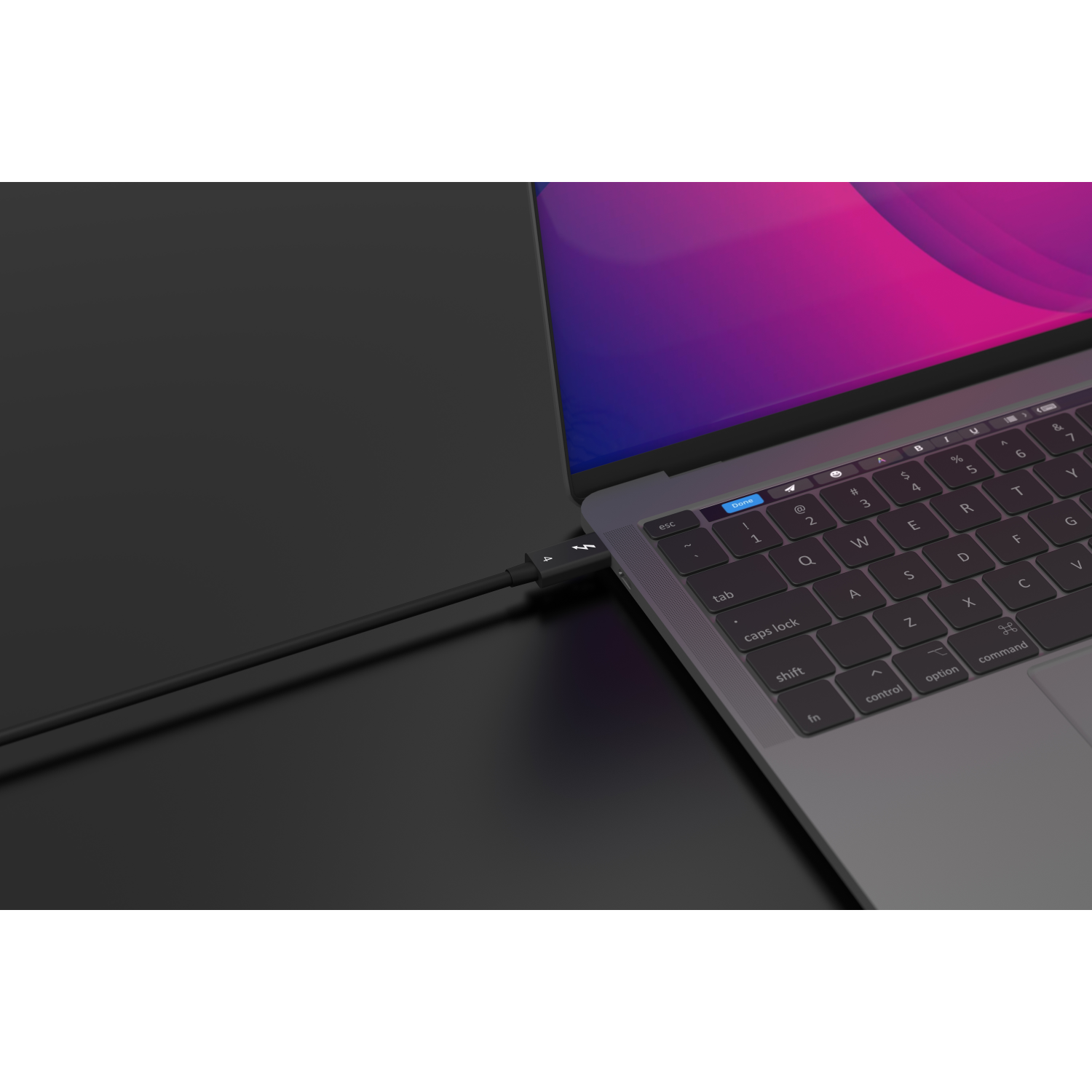 Laptop collegato a un cavo di ricarica nero. Sfondo scuro.