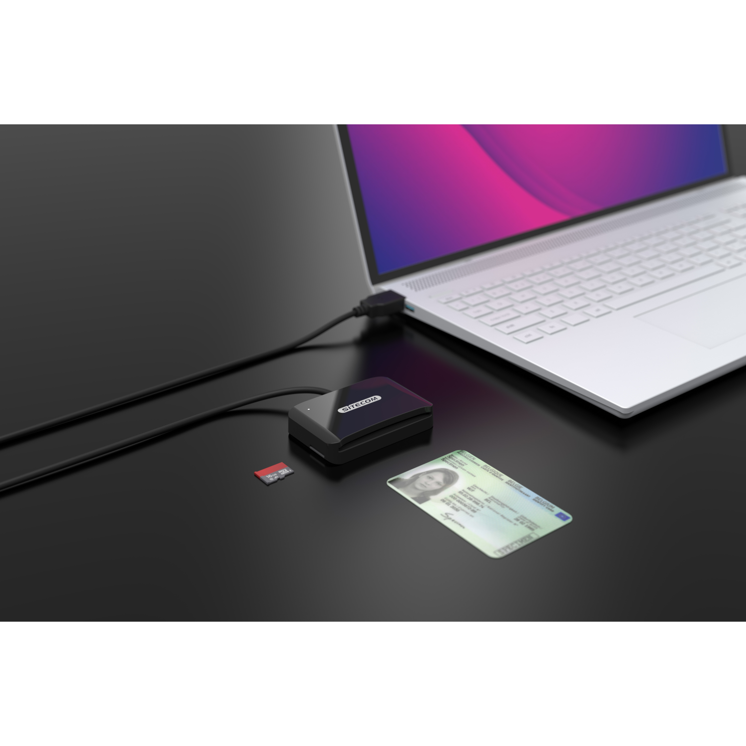 Laptop, lettore di schede, scheda SD e carta d'identità su superficie nera.