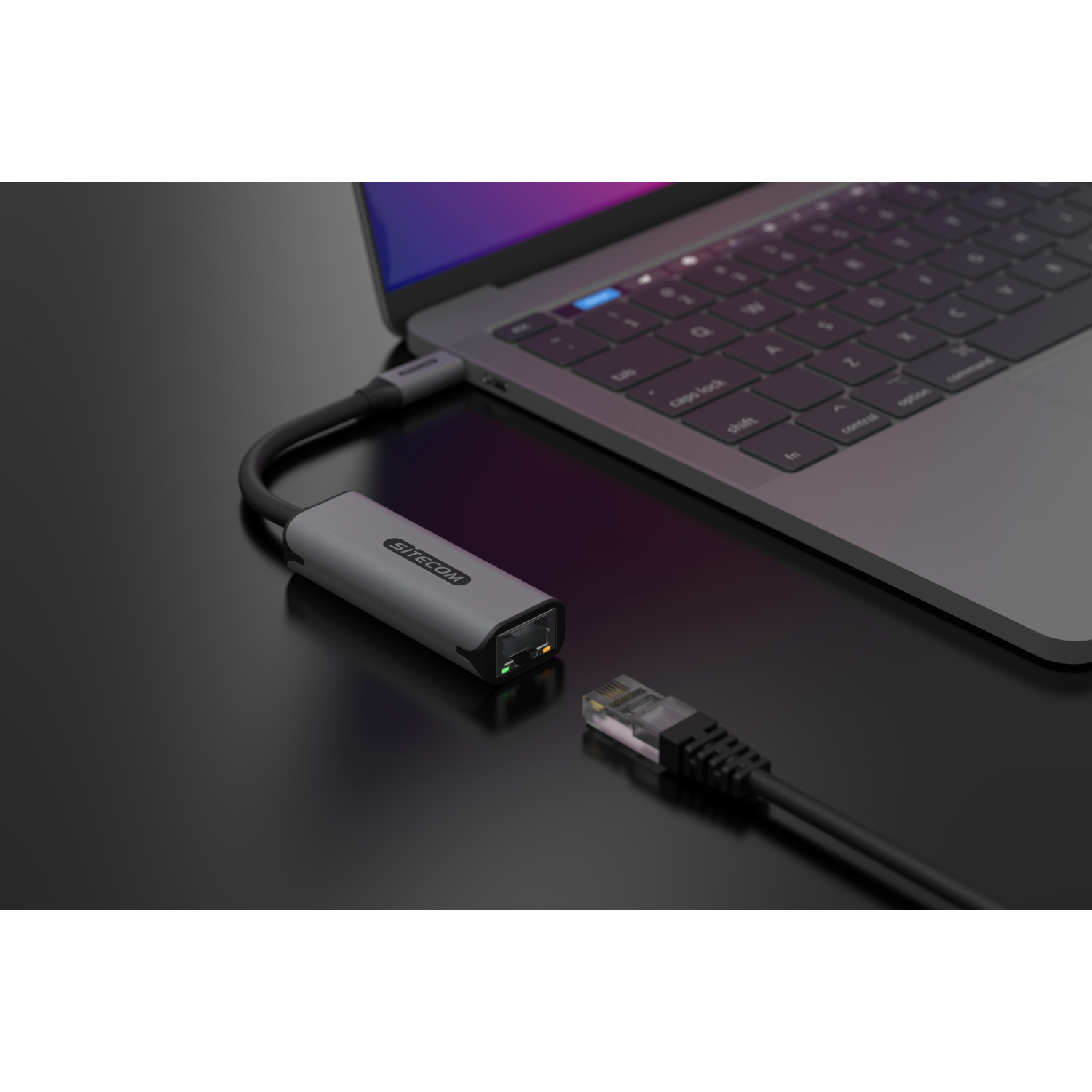 Ein Laptop, der über ein Ethernet-Kabel mit einem Adapter auf schwarzem Untergrund verbunden ist.