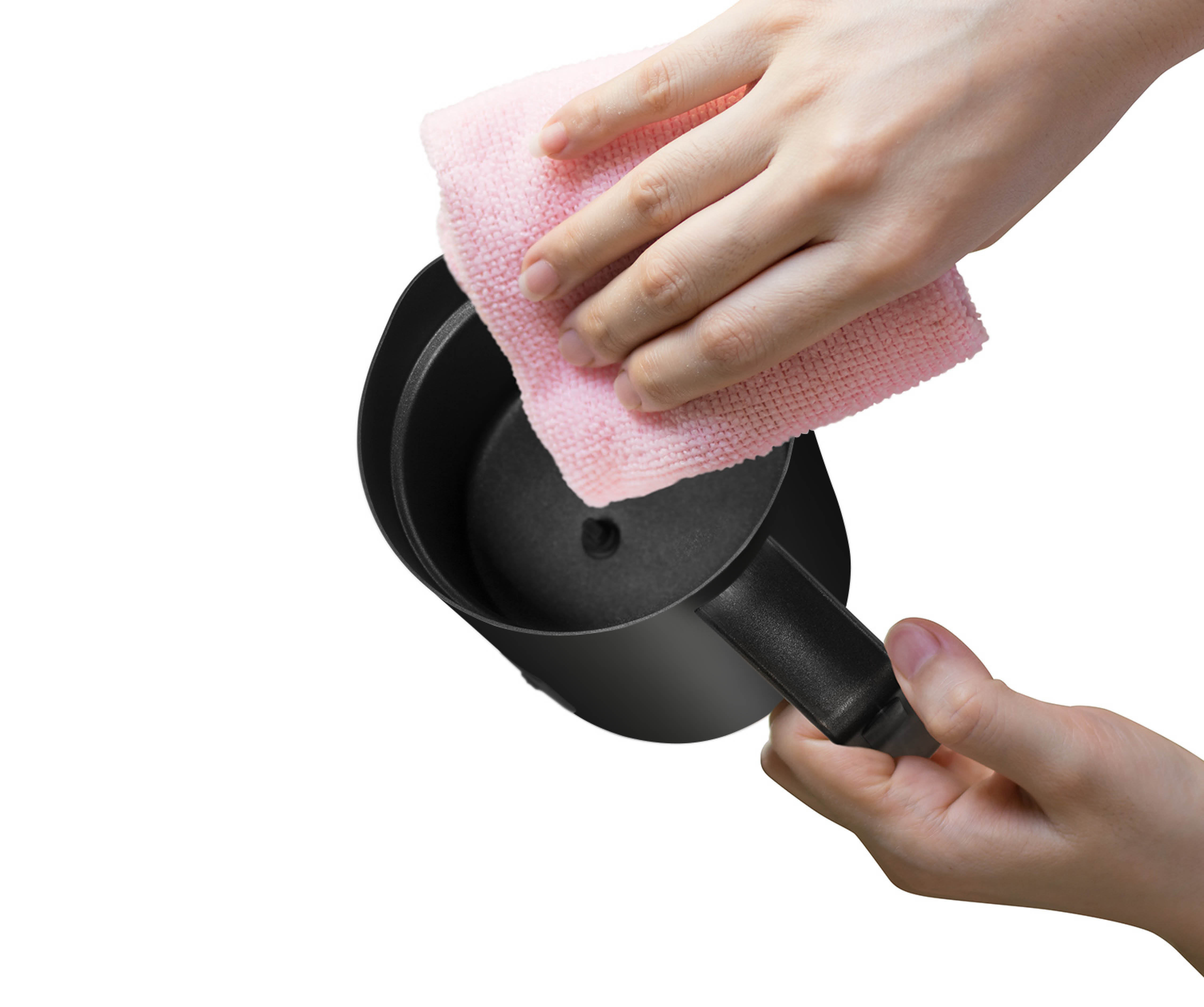 A hand is wiping the inside of a black jug with a pink cloth.