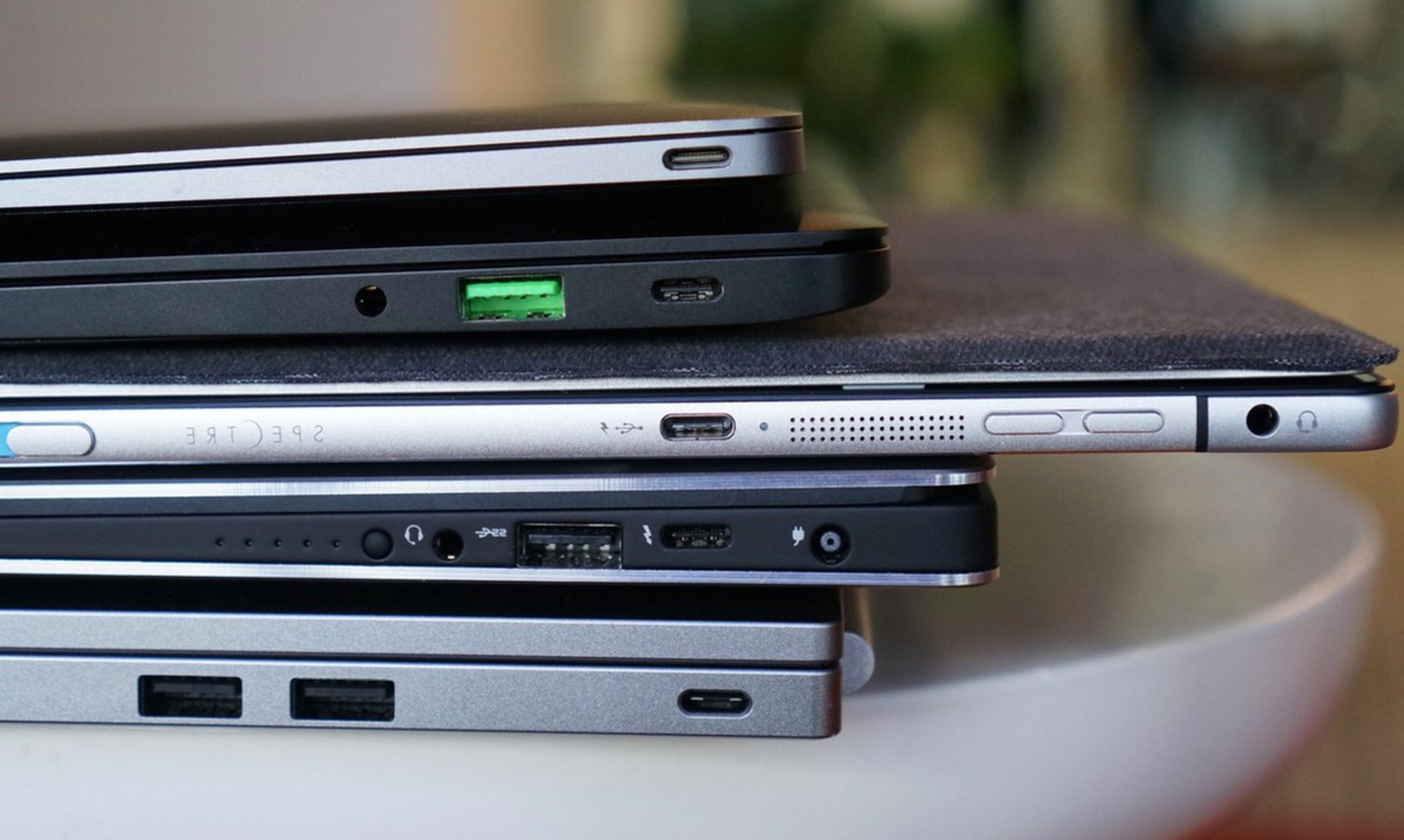 Laptops gestapelt. Sichtbare Anschlüsse: USB, USB-C und Kopfhöreranschluss.