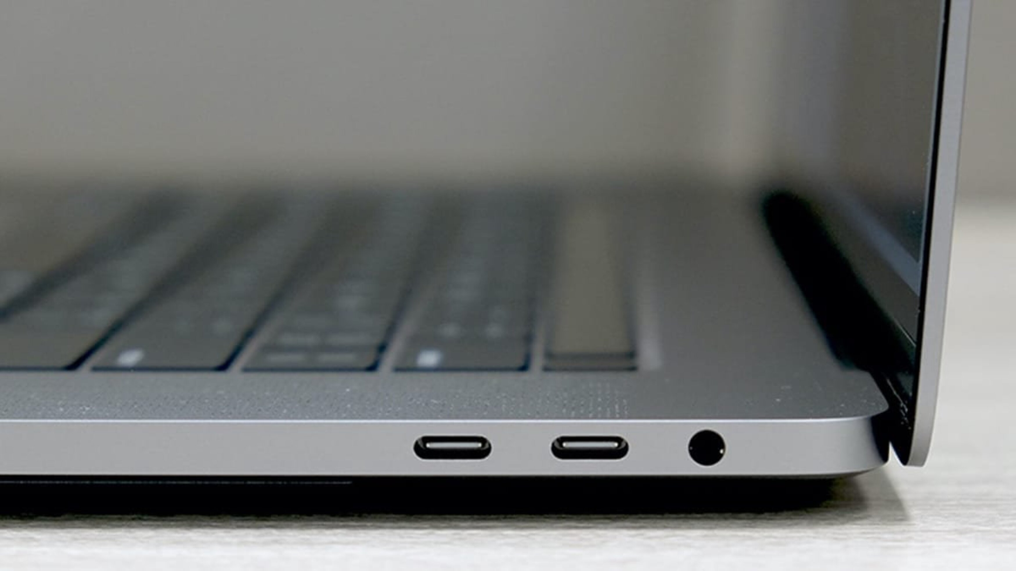 Gros plan sur le côté d'un ordinateur portable. Affiche les ports USB-C et une prise casque. Couleur grise.