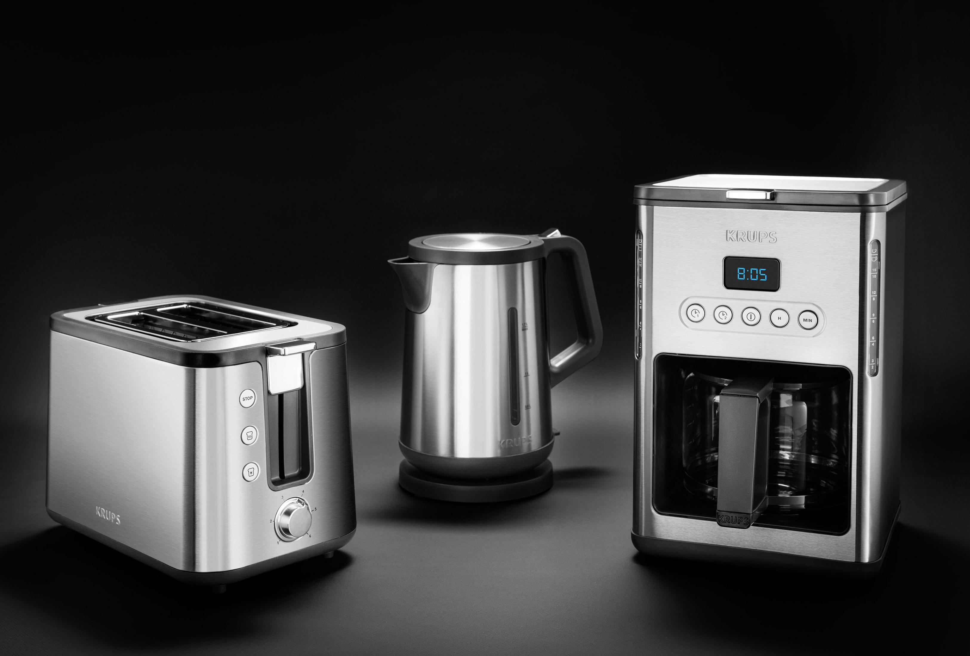 Toster, czajnik i ekspres do kawy ze stali nierdzewnej na czarnym tle.