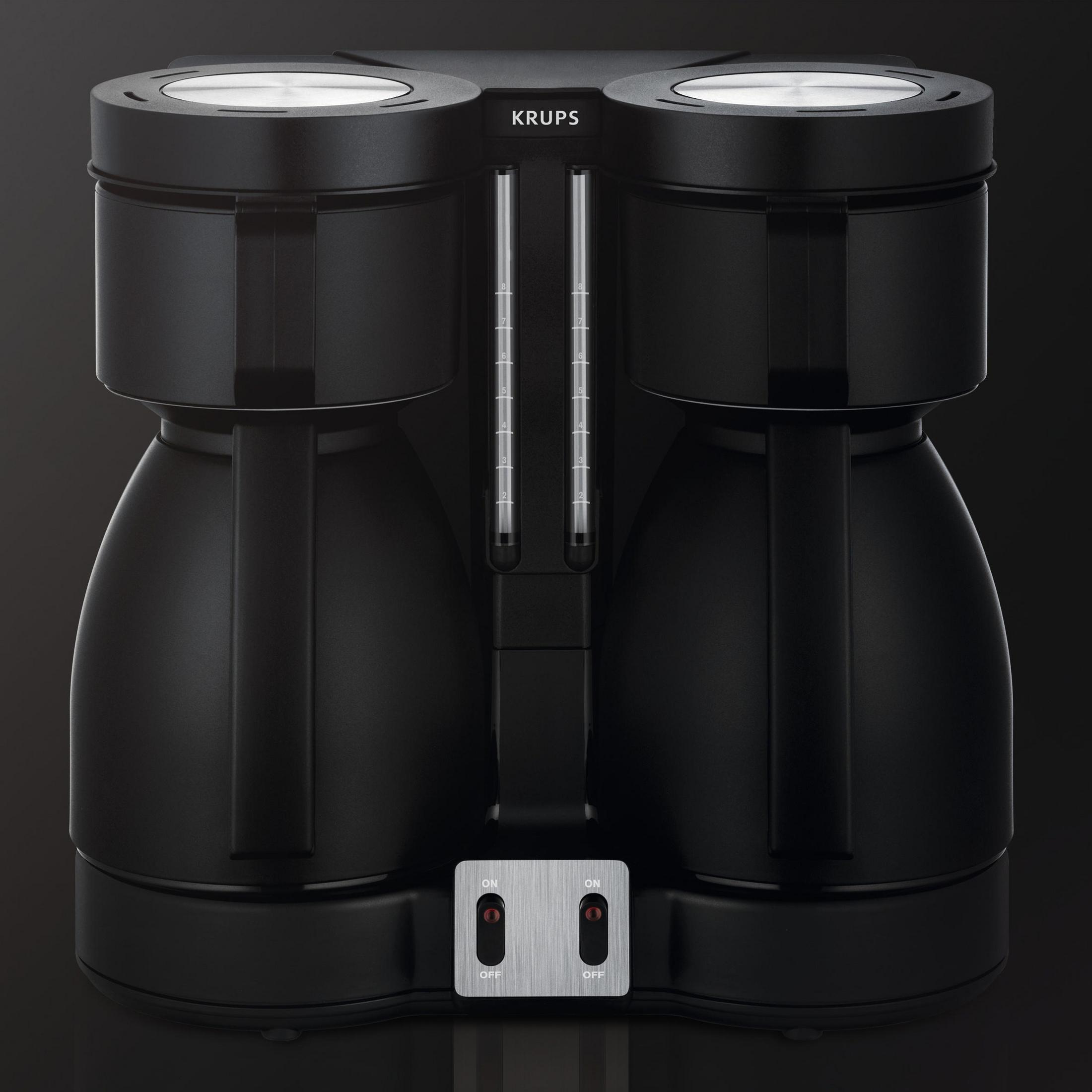 Czarny ekspres do kawy. Ma dwie oddzielne komory parzenia i wskaźnik poziomu wody, na ciemnym tle.