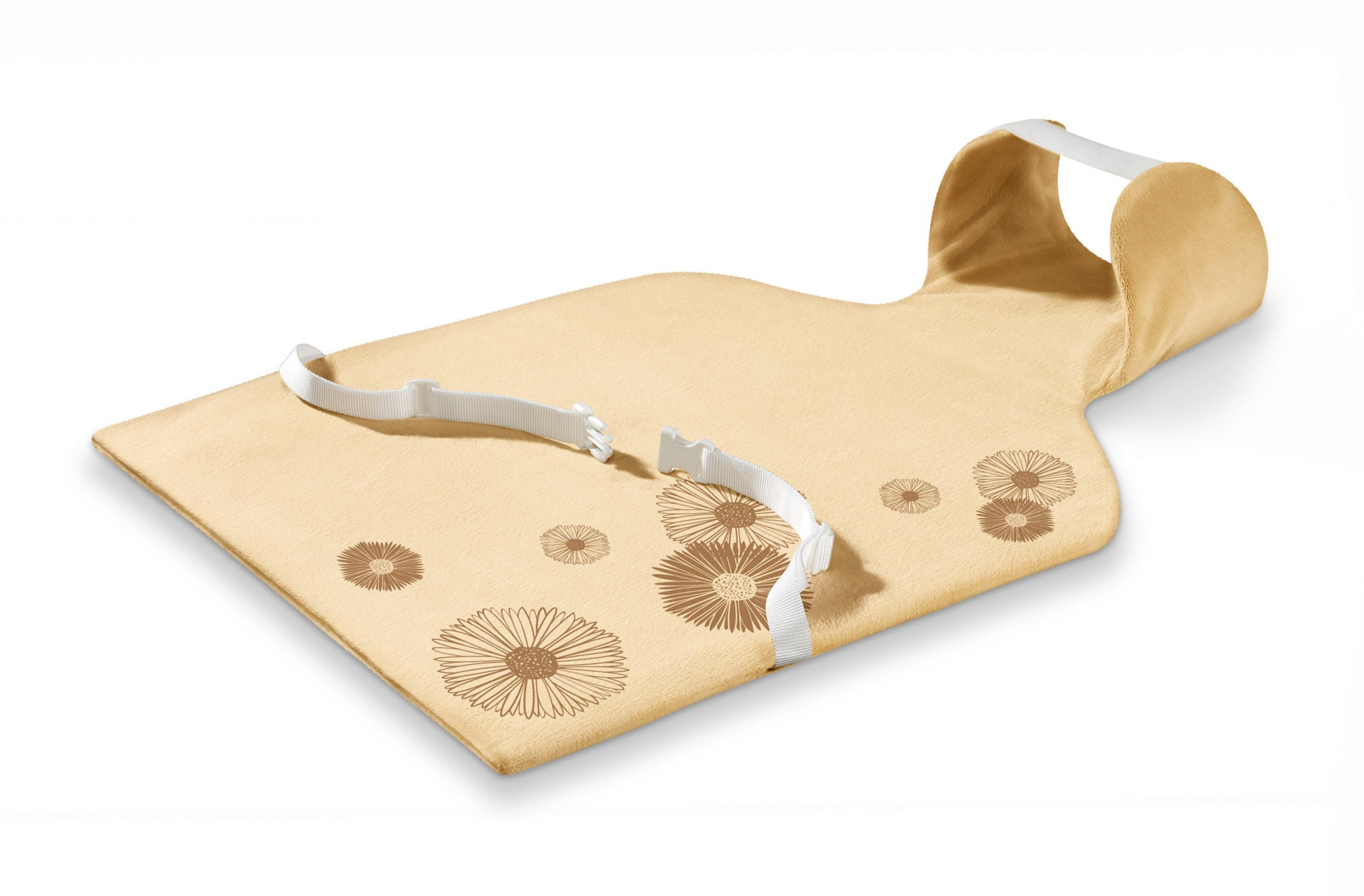 Ein beiges Babykissen mit Blumendesigns und weißen Riemen, auf weißem Hintergrund.