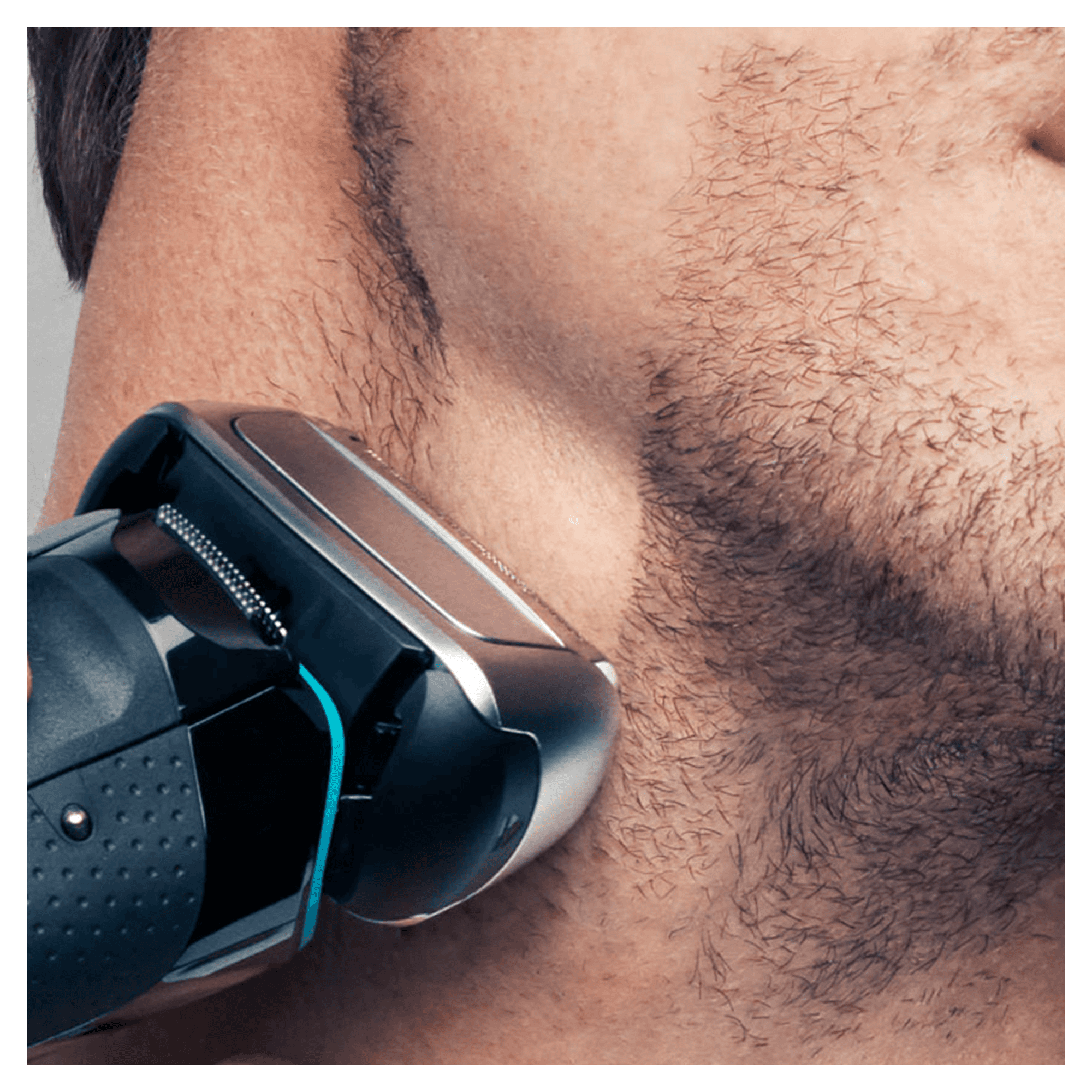 Mężczyzna goli brodę czarno-srebrną golarką elektryczną. Skóra jest widoczna w szczegółach.