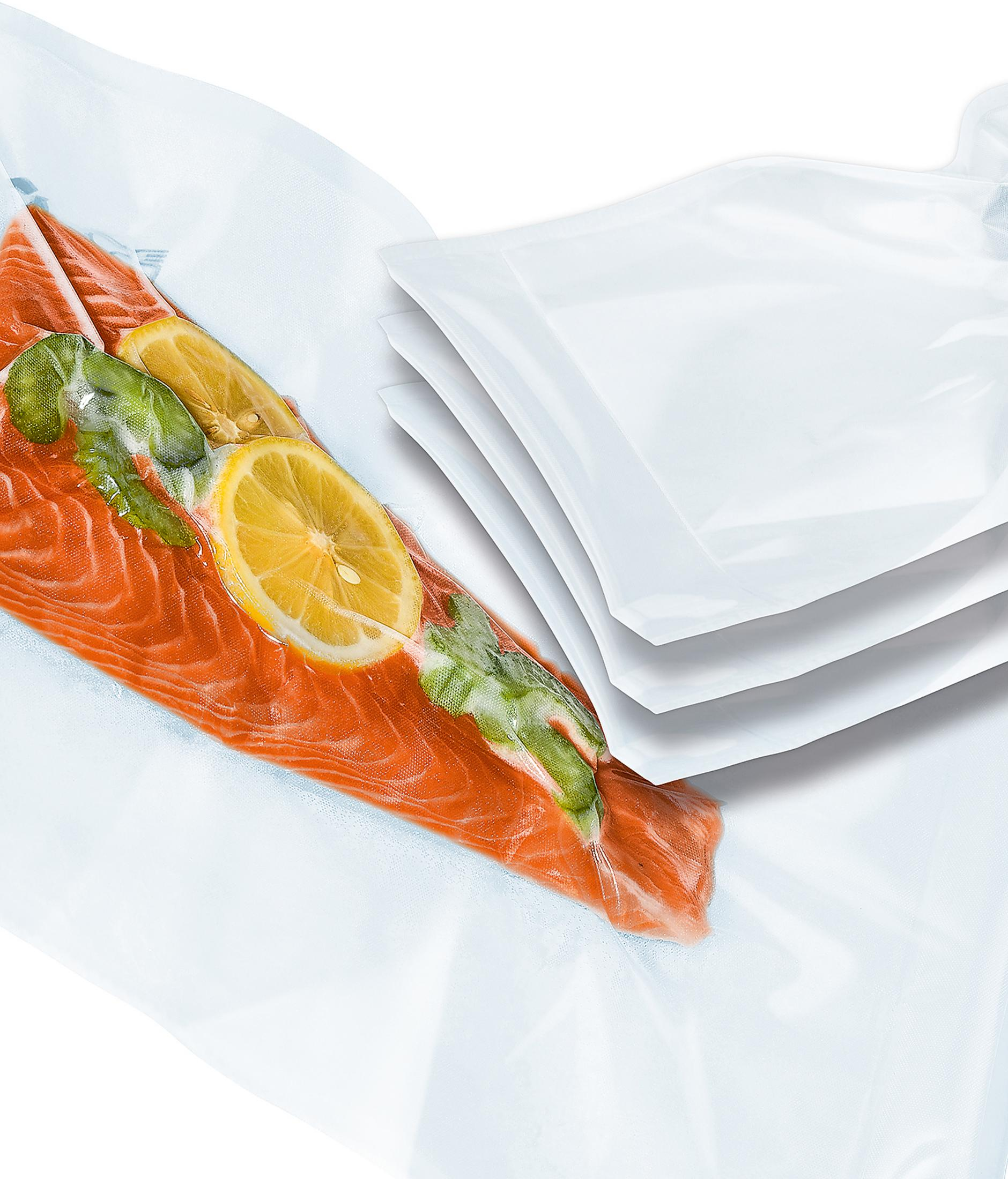 Lachsfilet mit Zitronenscheiben und Kräutern, vakuumverpackt in einem Klarsichtbeutel. Weiße Beutel daneben.