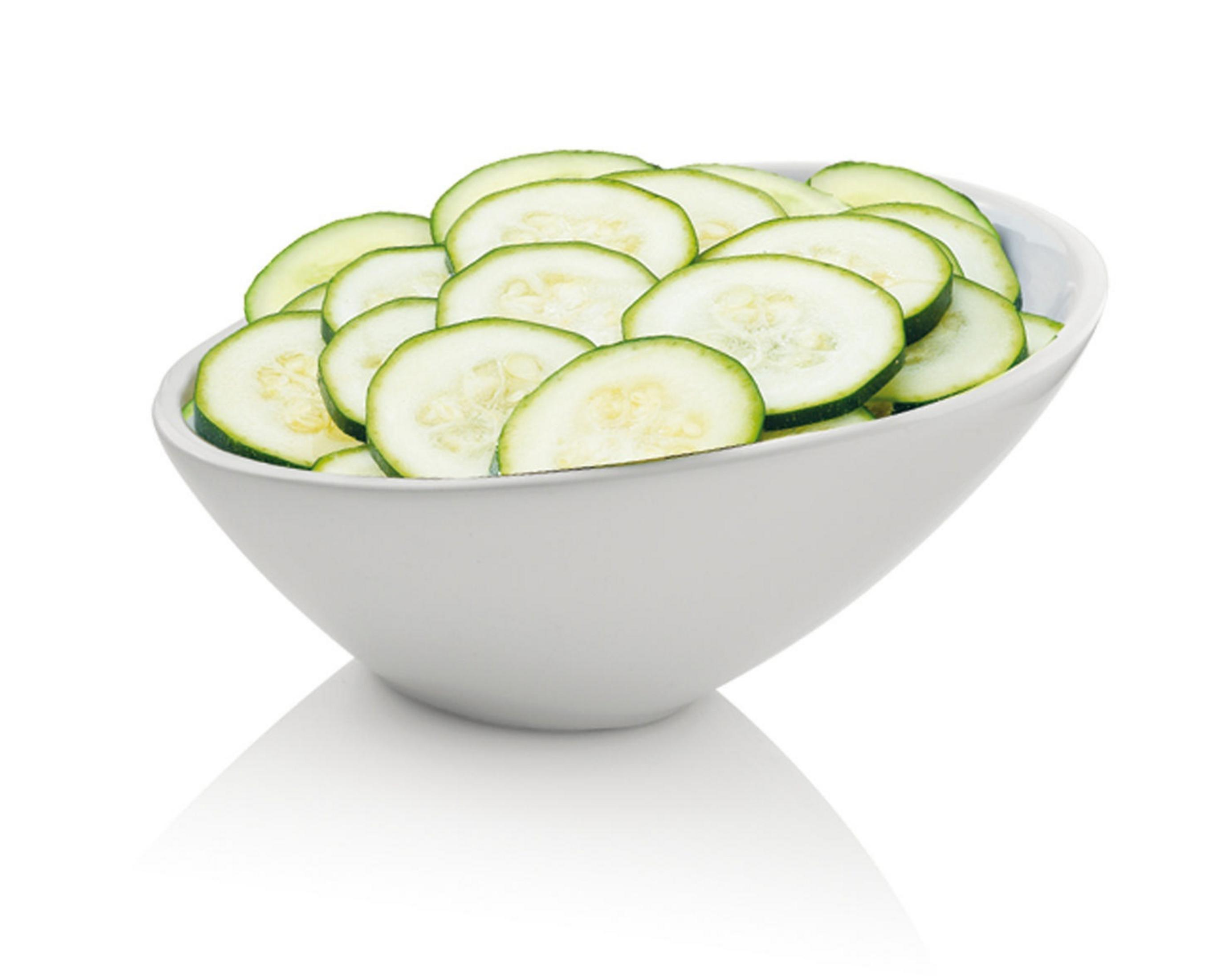 Weiße Schüssel gefüllt mit Gurkenscheiben, freigestellt auf weißem Grund.