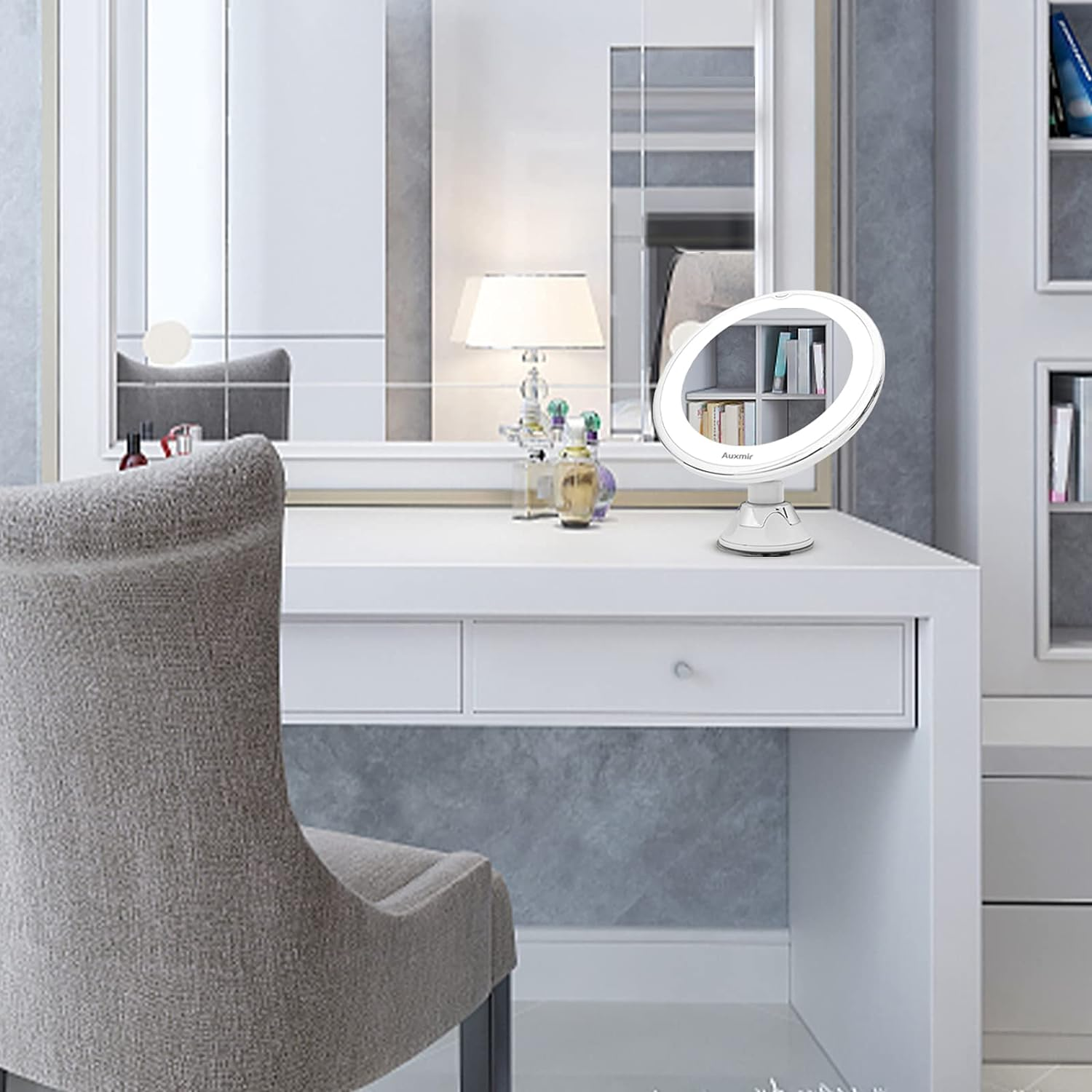 Weißer Schminktisch mit beleuchtetem Ringlicht, Spiegel und Kosmetik, mit grauem Stuhl.