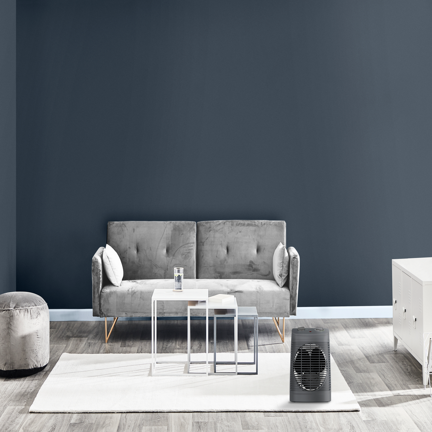 Salon z szarą sofą, białymi stolikami i czarnym grzejnikiem.