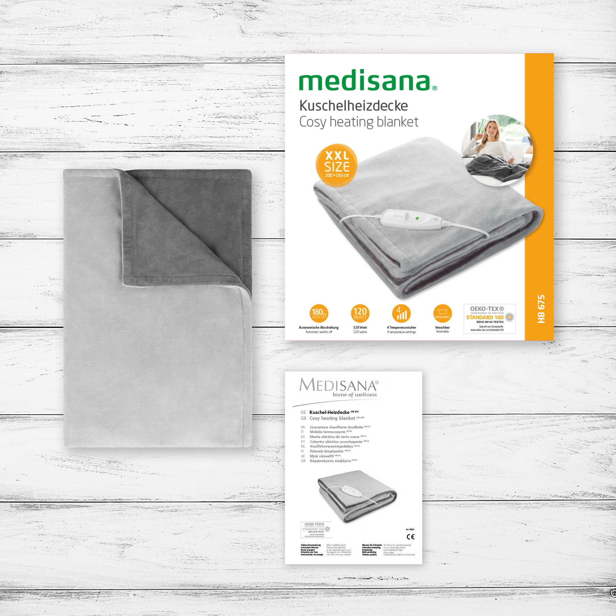 Szary koc grzewczy z opakowaniem i broszurą na drewnianej powierzchni.