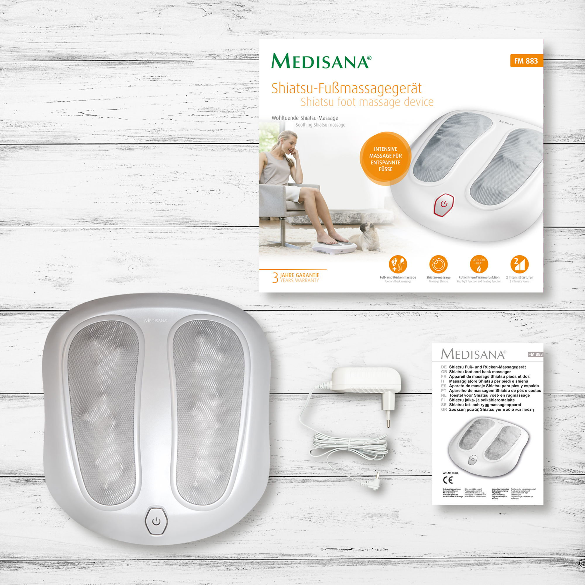 Masażer do stóp z akcesoriami. Szczegóły: masażer, zasilacz i małe pudełko z instrukcją.