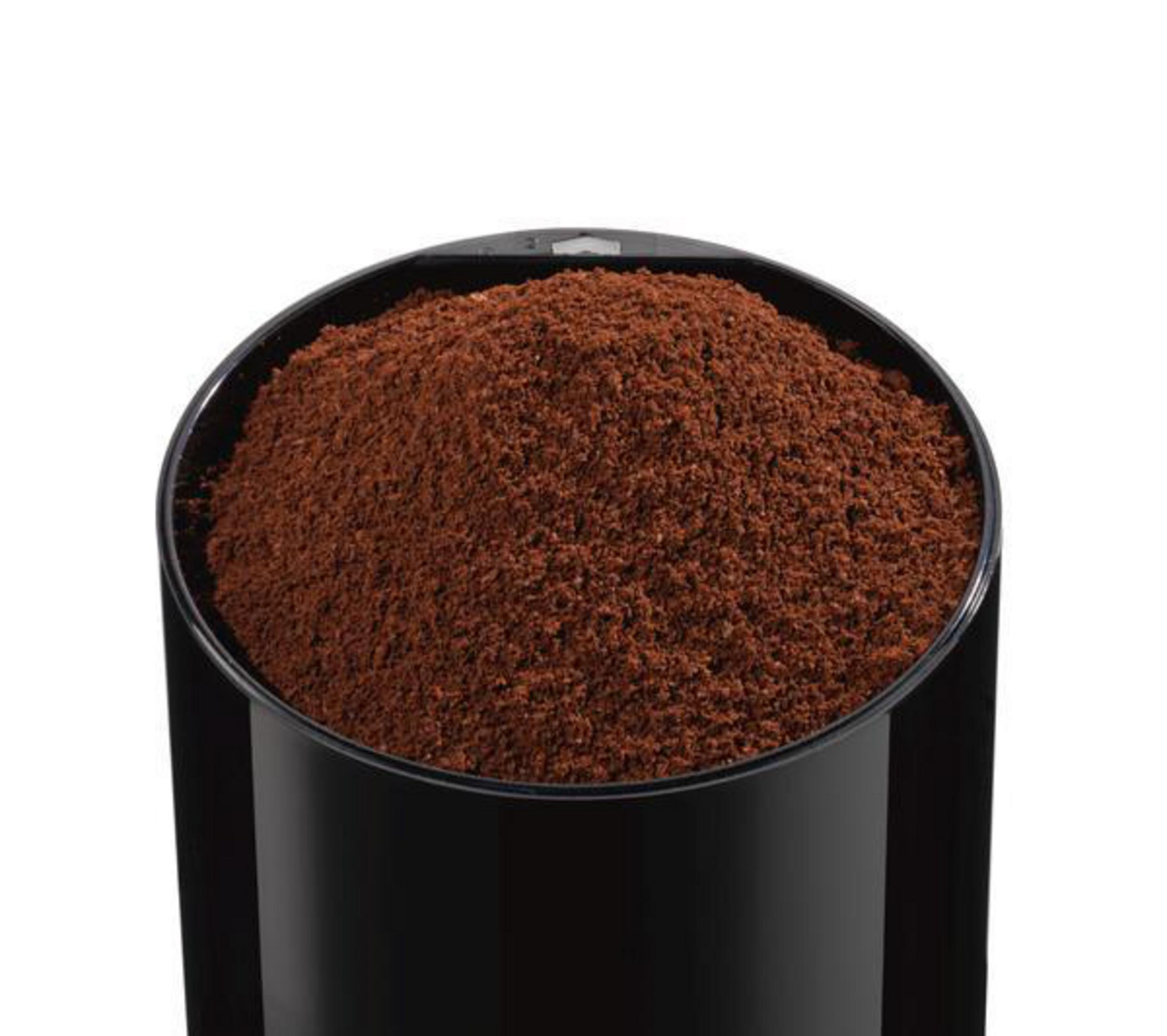 A black grinder filled with ground coffee. The coffee is a dark brown color.