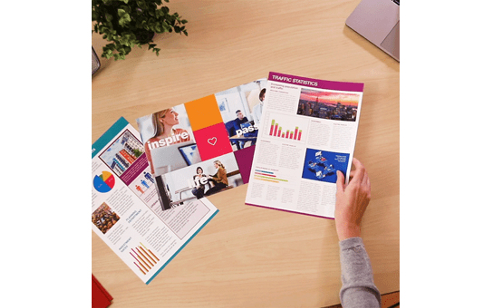 Ręce trzymające raport Statystyki Ruchu z innymi wydrukami na drewnianym biurku.