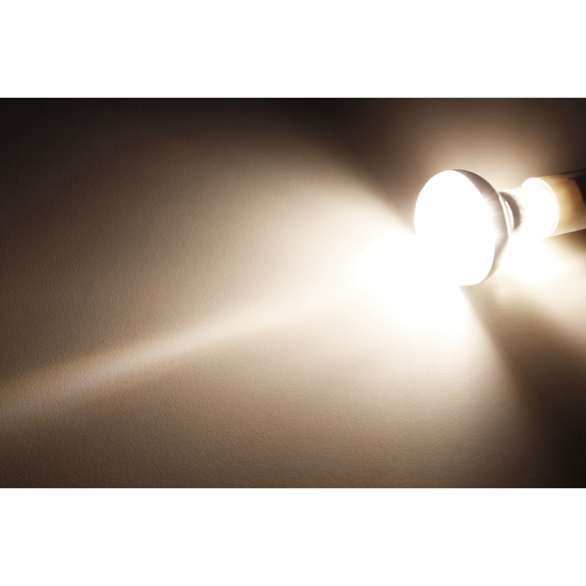 Helles Licht von einer Glühbirne auf einer beigen Oberfläche. Das Licht breitet sich aus.