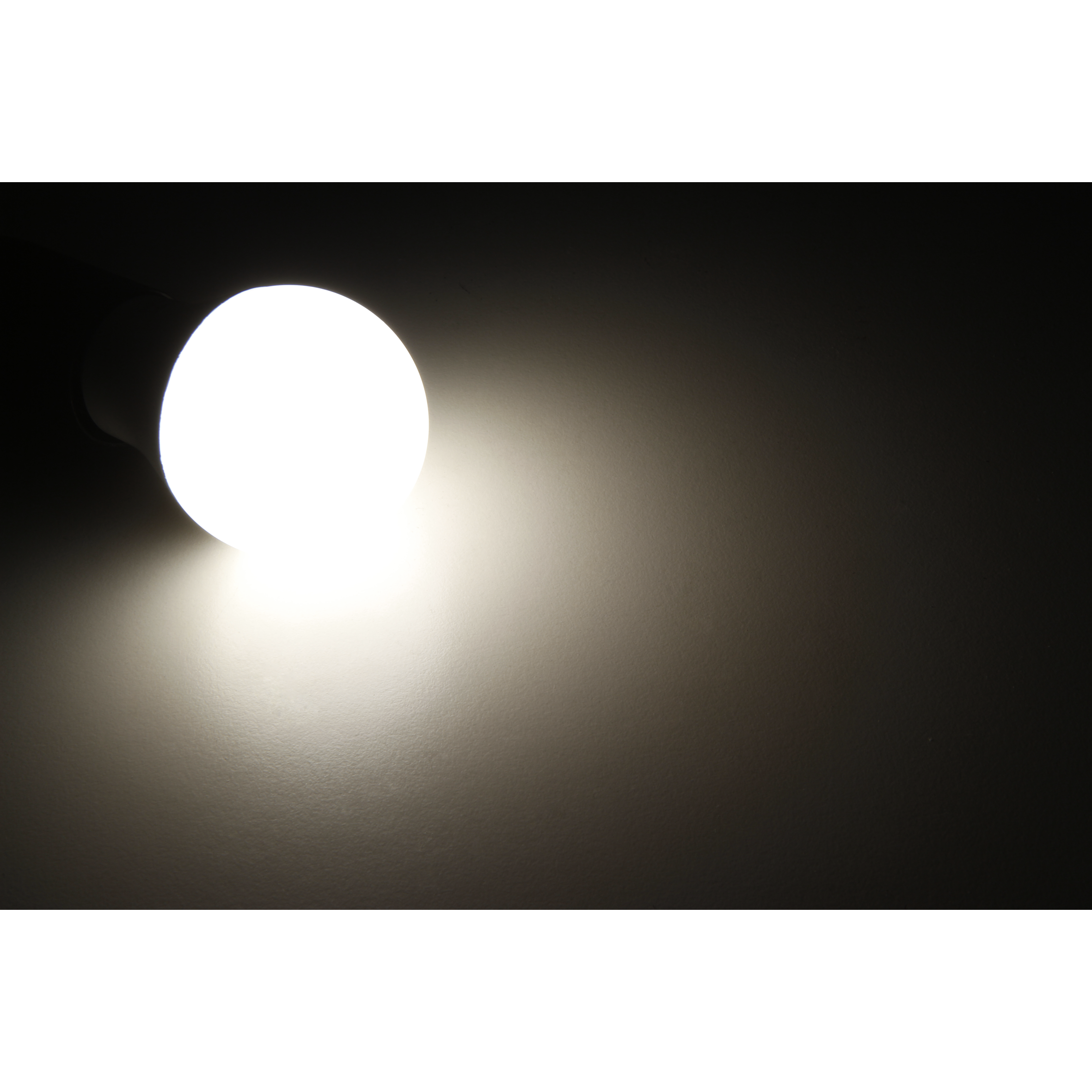 Eine leuchtende Glühbirne auf dunklem Hintergrund. Das Licht scheint auf die Wand.