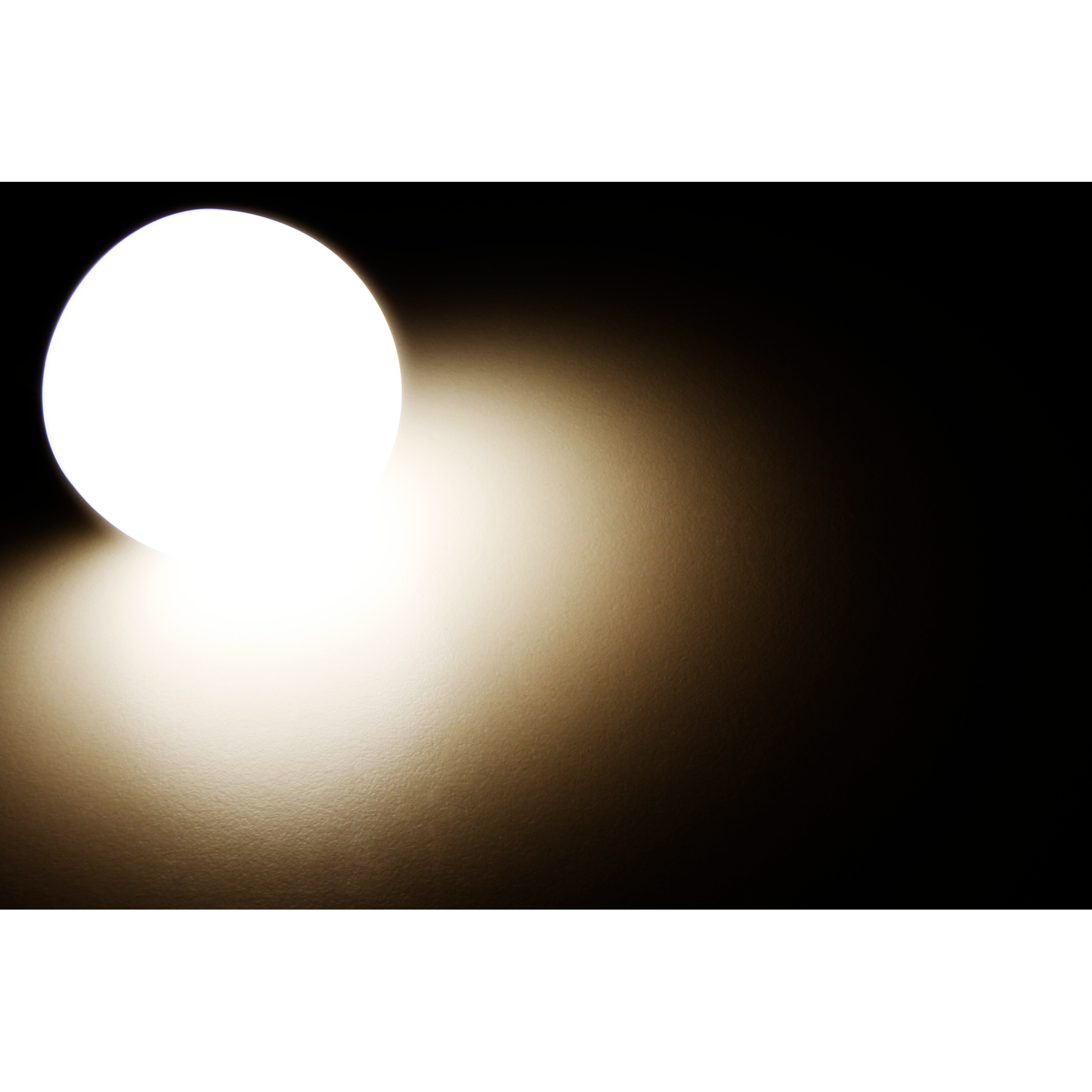 Ein helles, weißes Licht scheint auf eine dunkle Oberfläche und erzeugt einen warmen Farbverlauf.