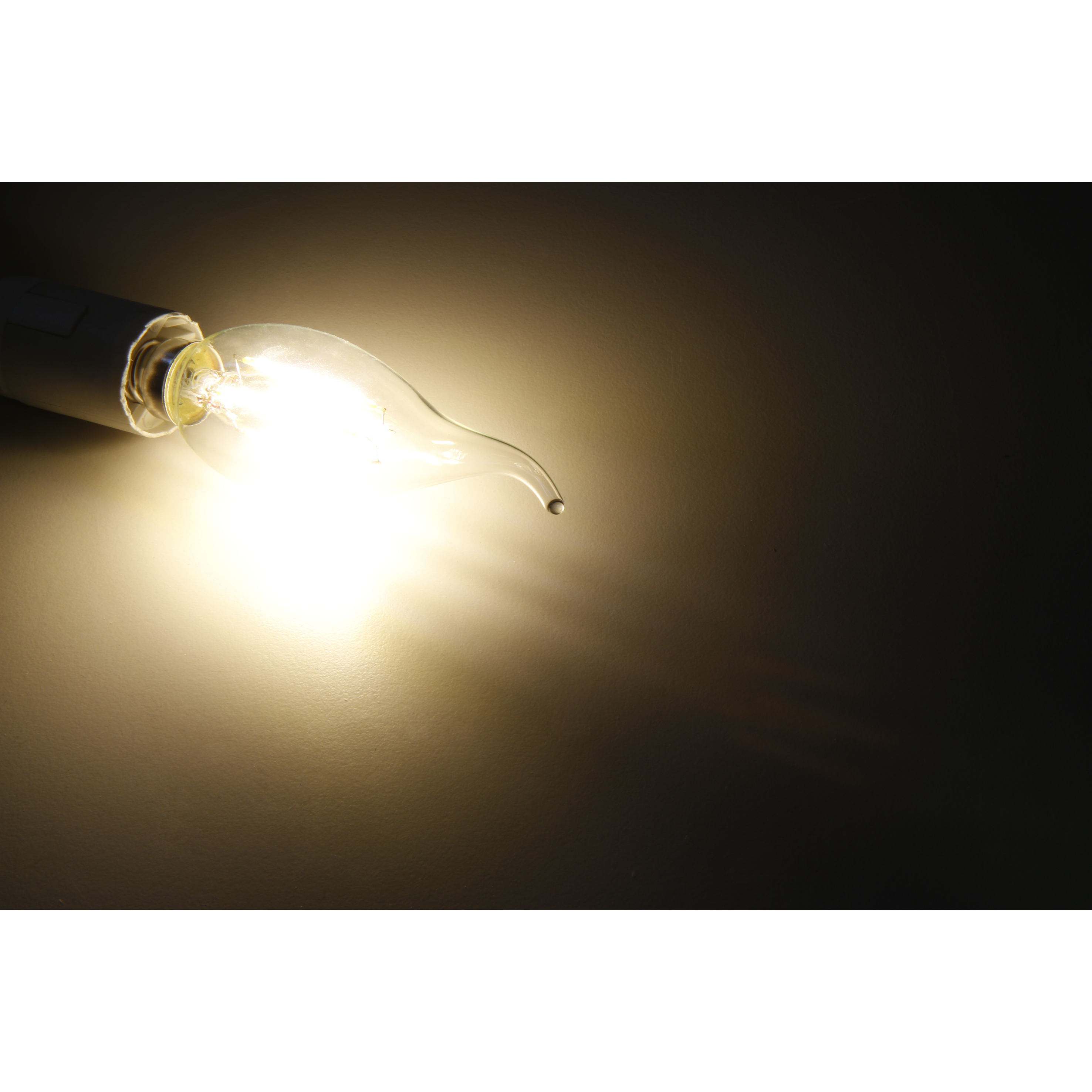Glühbirne mit gebogener Spitze, die warmes Licht ausstrahlt, vor dunklem Hintergrund.