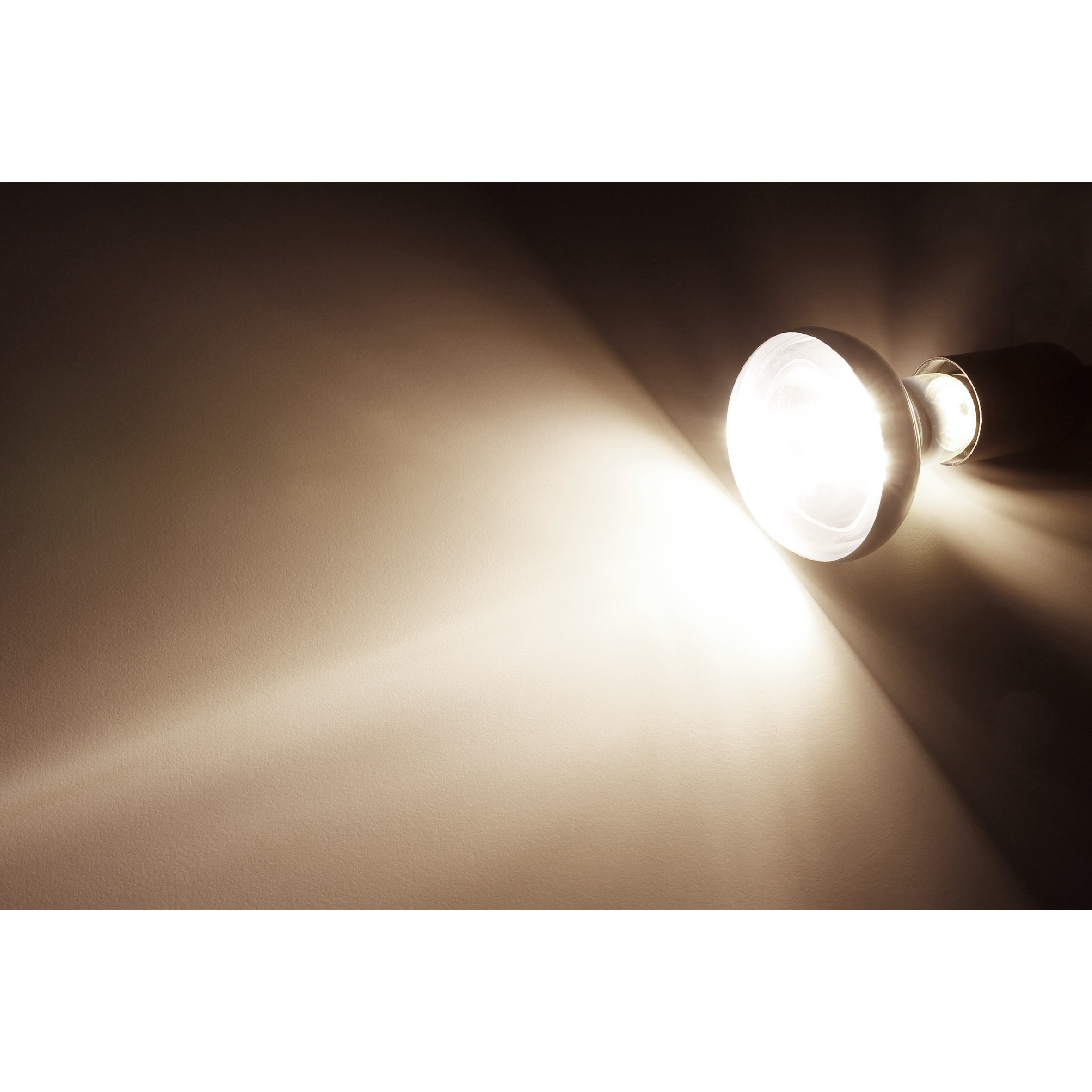 Ein Scheinwerfer beleuchtet eine Wand und erzeugt einen hellen, fokussierten Lichtstrahl.
