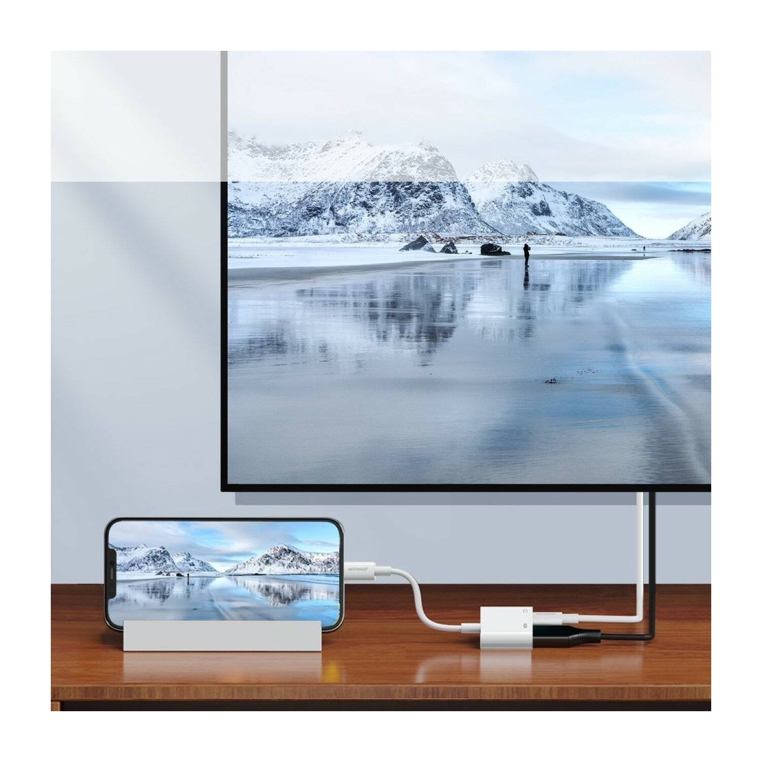 Ein Telefon auf einem Ständer ist über ein Kabel mit einem Fernseher verbunden. Auf beiden Bildschirmen ist eine Schneelandschaft zu sehen.