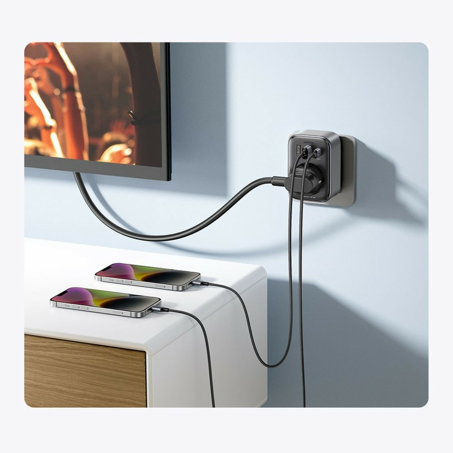 Zasilacz podłączony do ściany, ładujący dwa telefony. Adapter ma wiele portów i wtyczek.