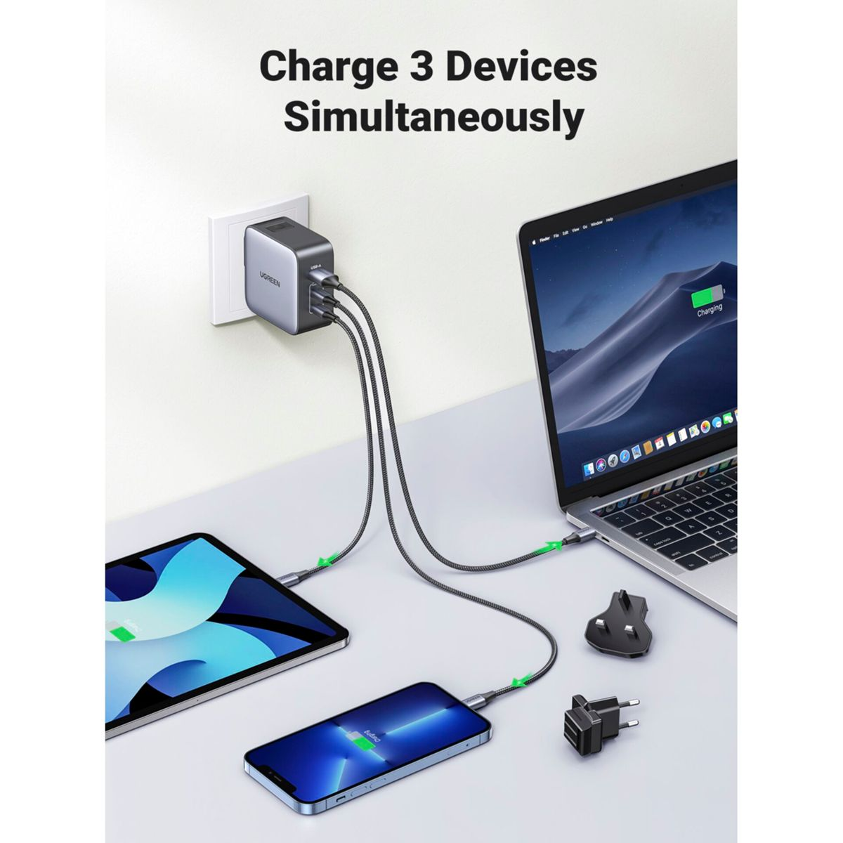 A charging hub with 3 cables connected to a tablet, phone, and laptop. White wall in the background.