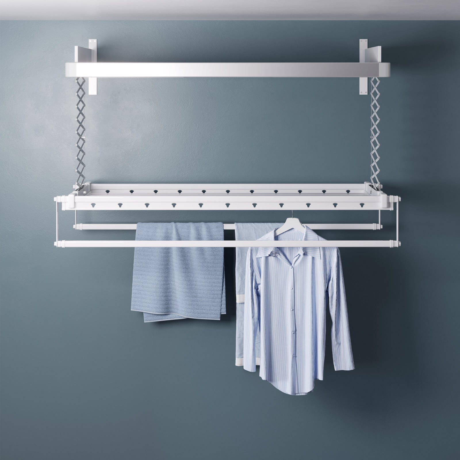 Stendibiancheria bianco montato a soffitto con vestiti appesi e una parete blu.