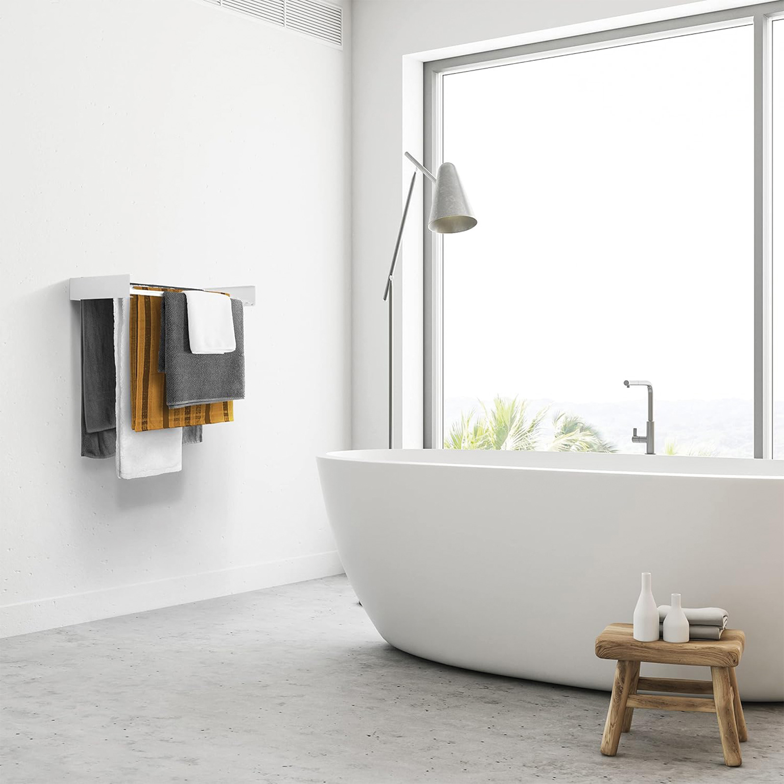 Bagno con asciugamani sulla parete e una vasca da bagno. Finestra grande, pareti bianche.