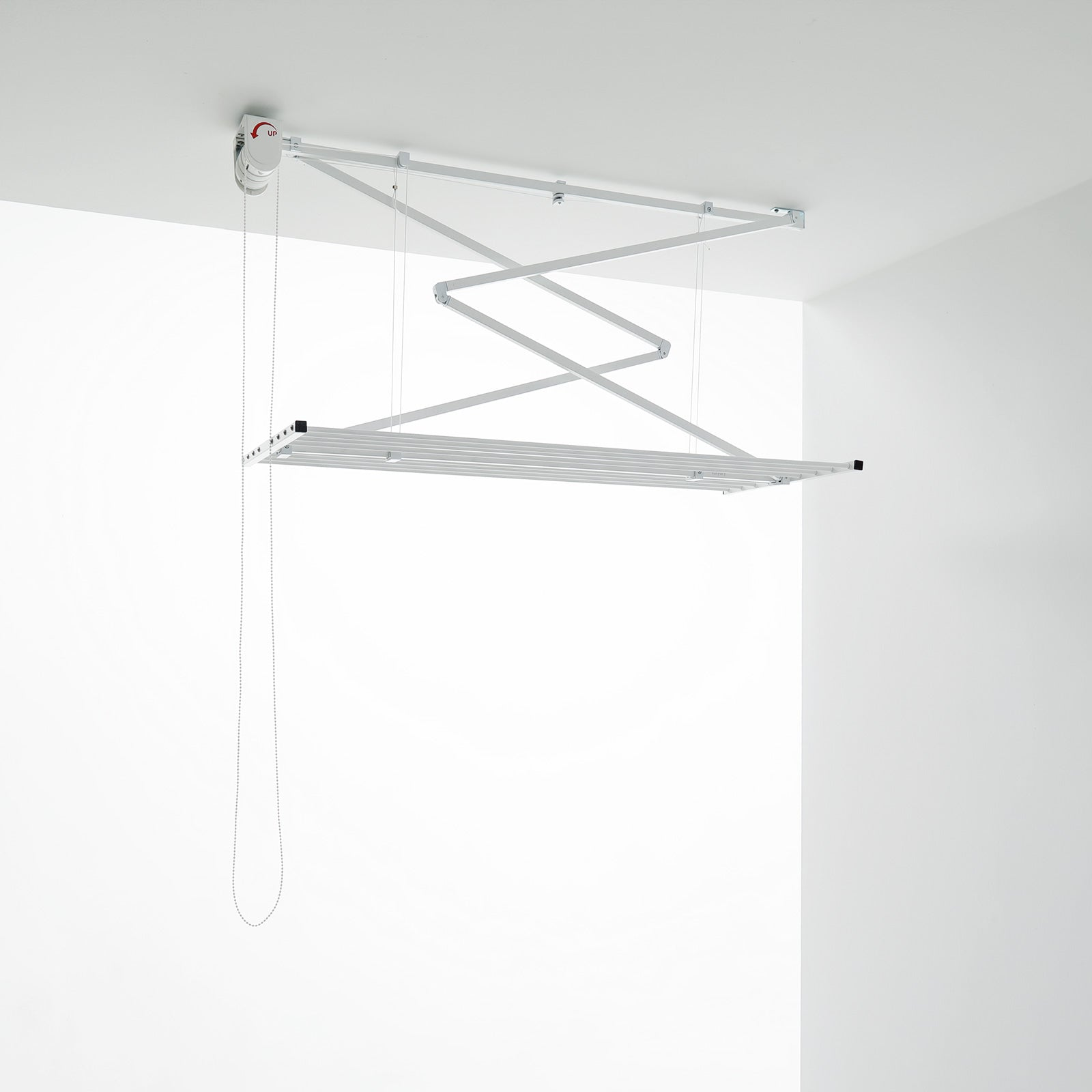 An der Decke montierter Wäschetrockner. Weißes Gestell, hängt von der Decke. Weiße Wände.