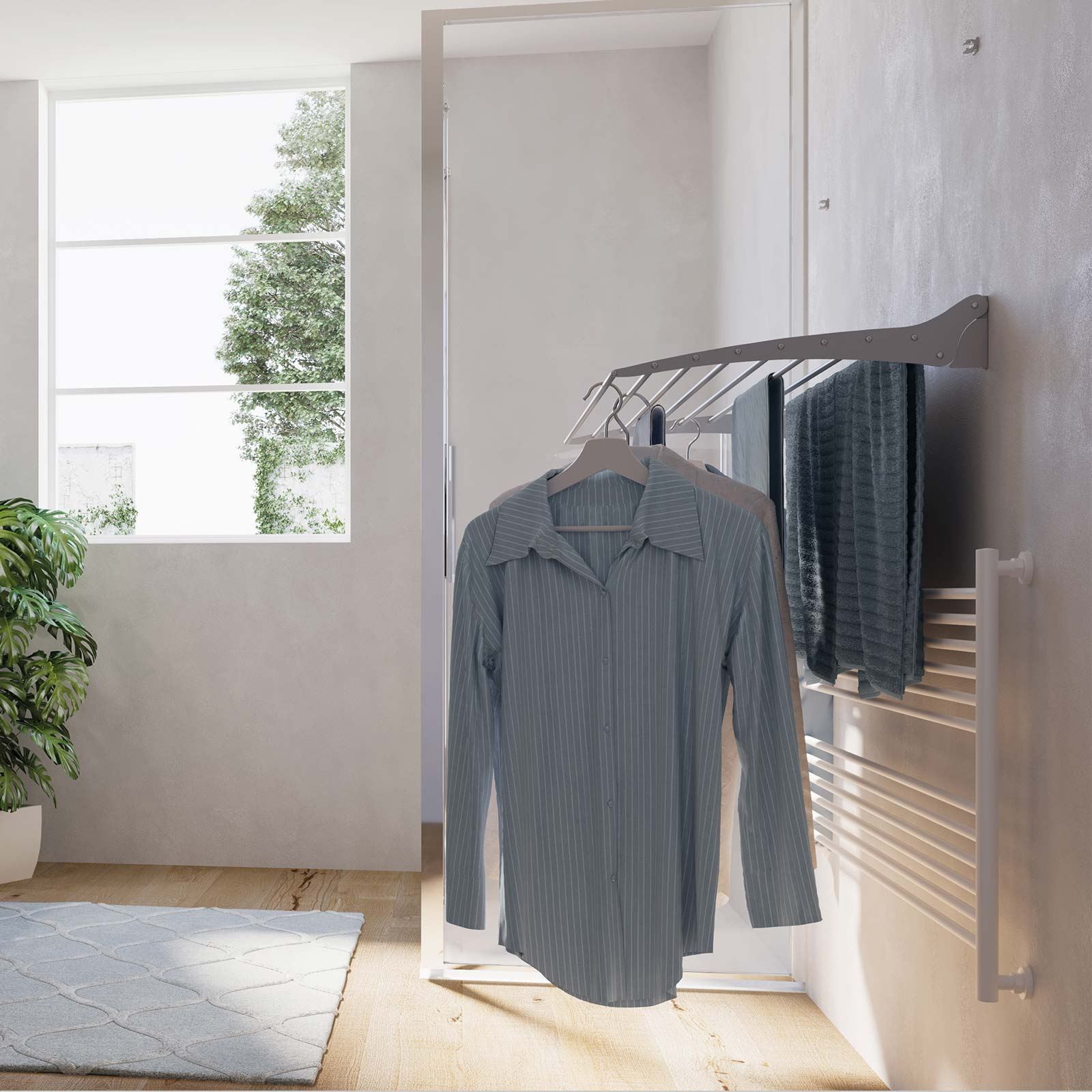 Un sistema per appendere il bucato con una camicia e asciugamani. Muro bianco, finestra sullo sfondo. Colori chiari.