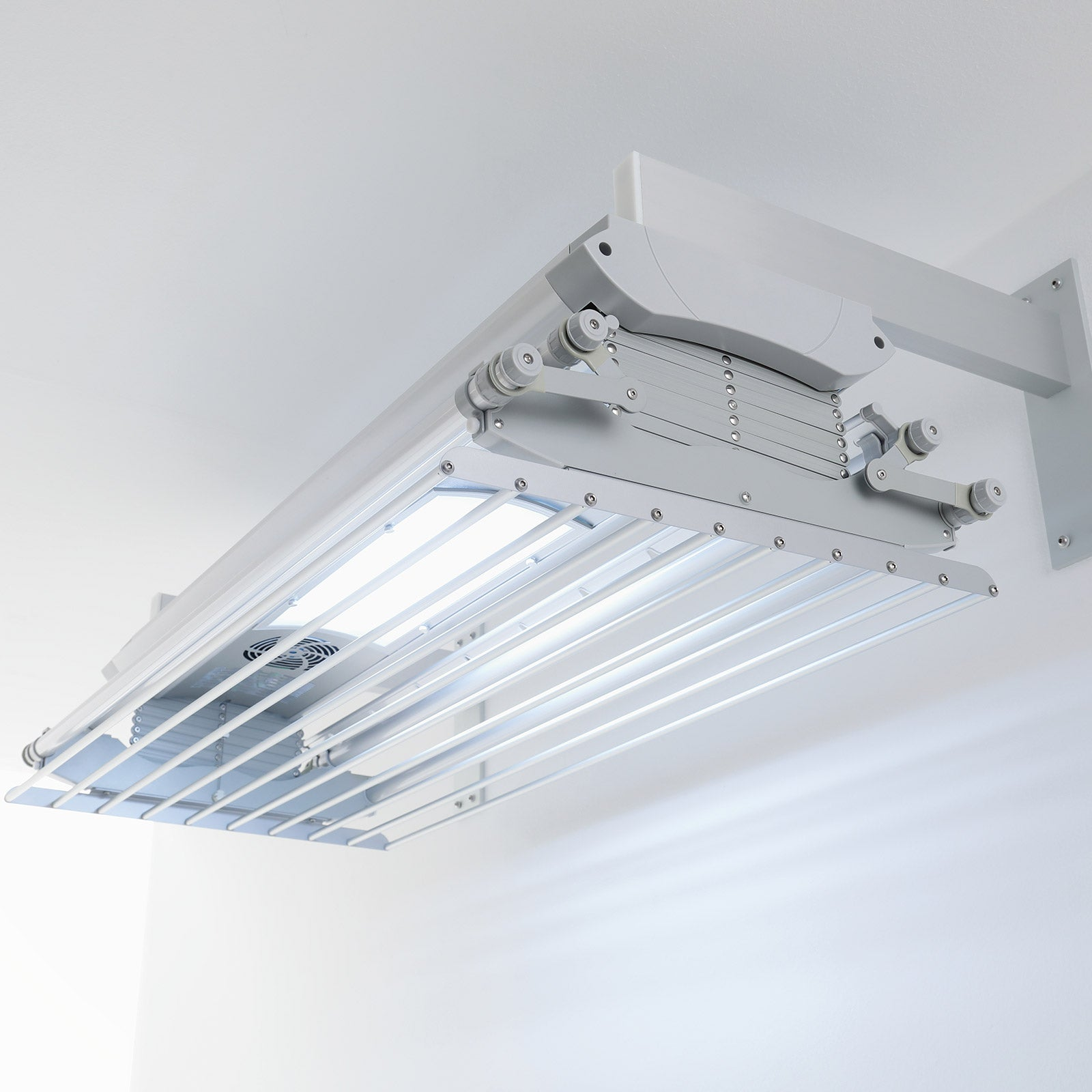 Un'asciugatrice bianca montata a soffitto. Ha più aste per appendere i vestiti e un apparecchio di illuminazione.