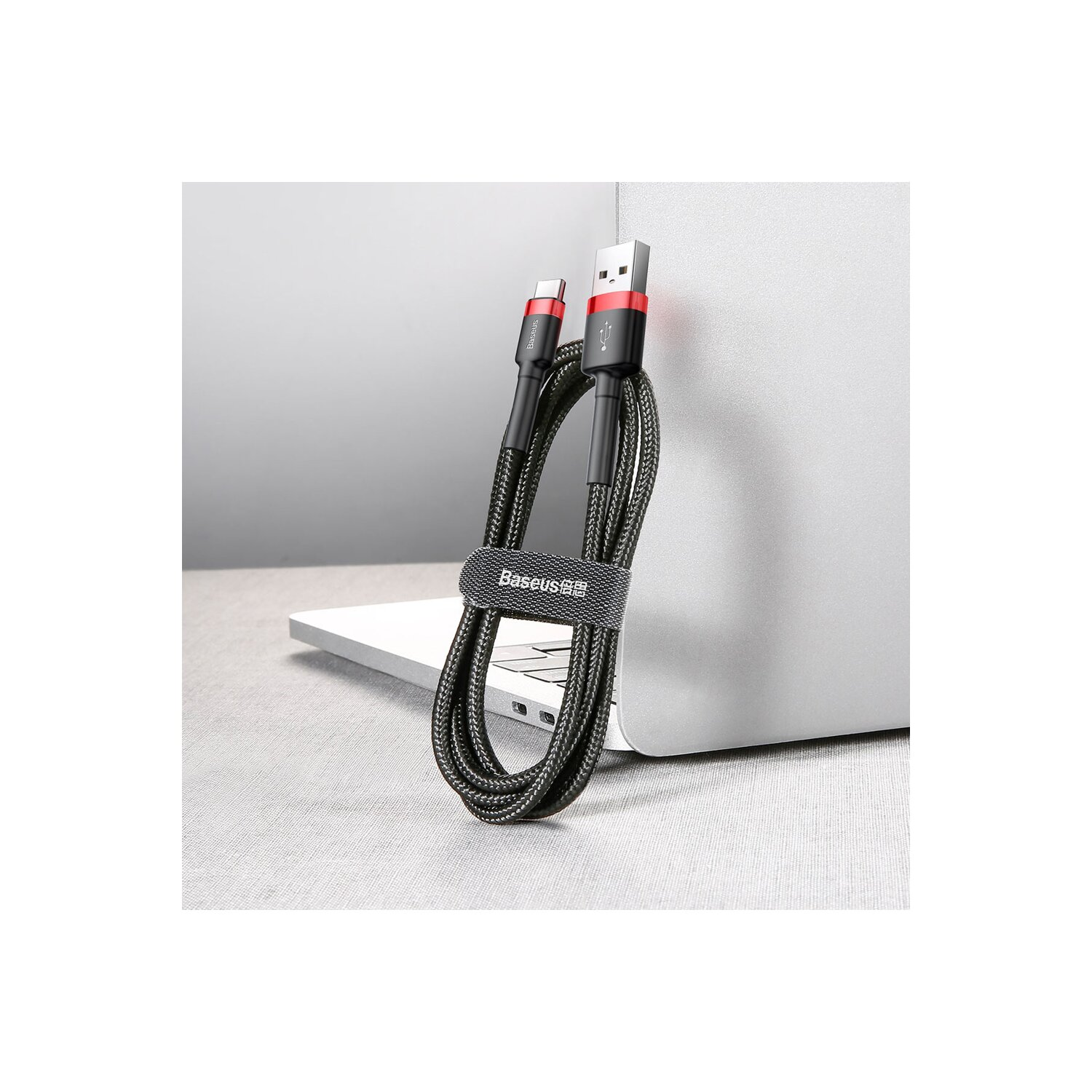 Czarny i szary kabel USB-C z logo Baseus. Jest owinięty paskiem i leży na stole.