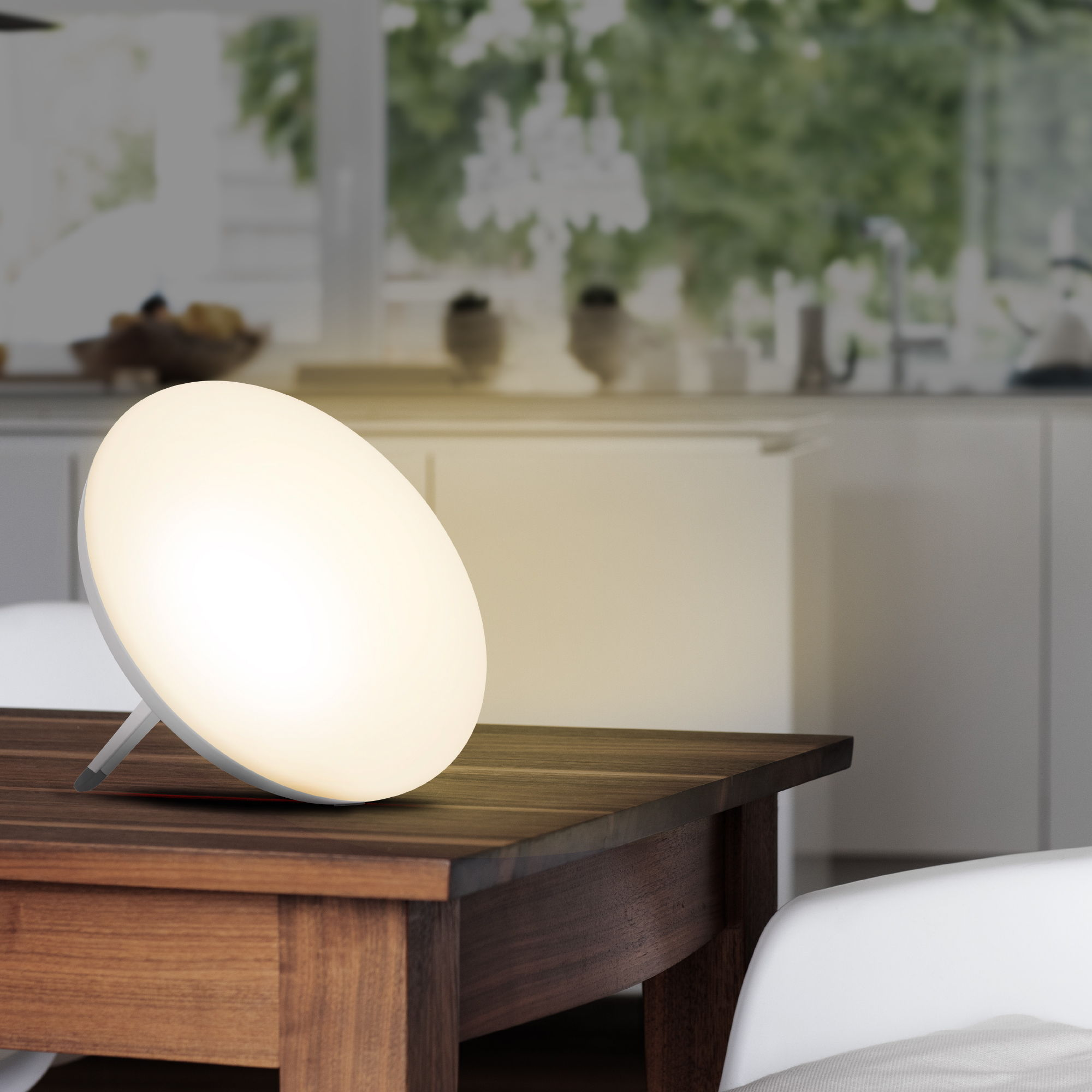 Eine weiße, runde Lampe auf einem braunen Holztisch. Rechts ein weißer Stuhl.