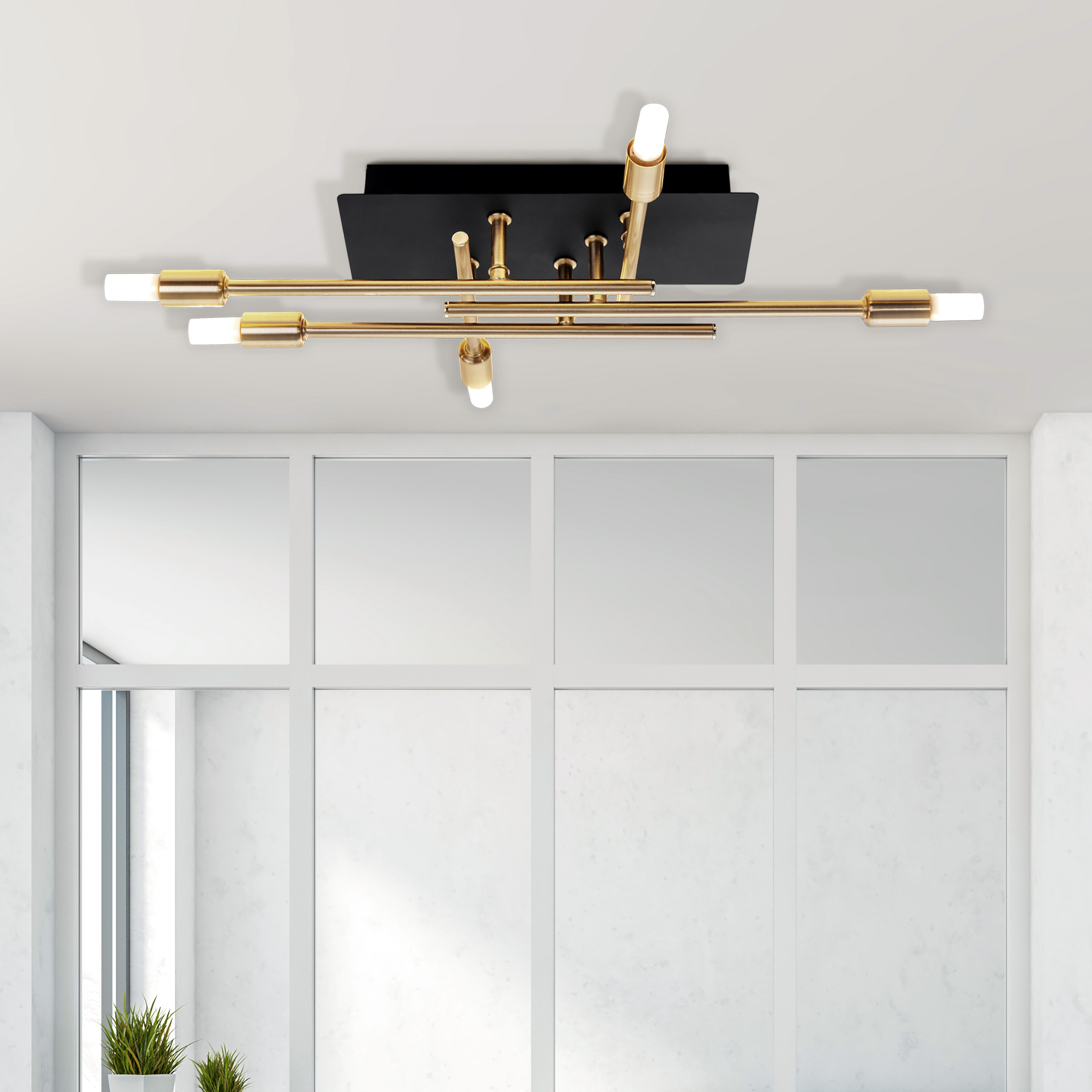 Moderne Deckenleuchte mit Gold- und Schwarzdesign. Der Hintergrund ist eine weiße Wand mit Fenster.