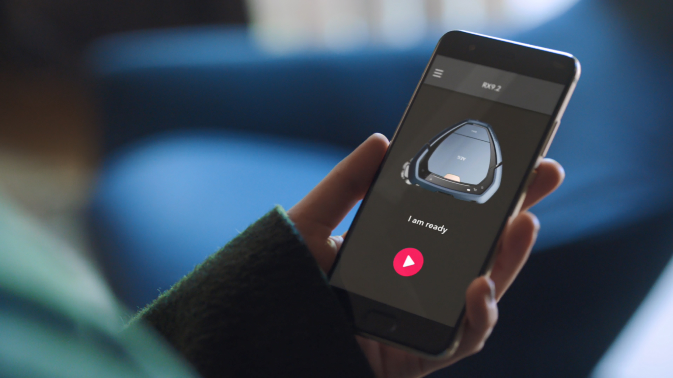 Osoba trzyma telefon wyświetlający interfejs aplikacji robota sprzątającego.