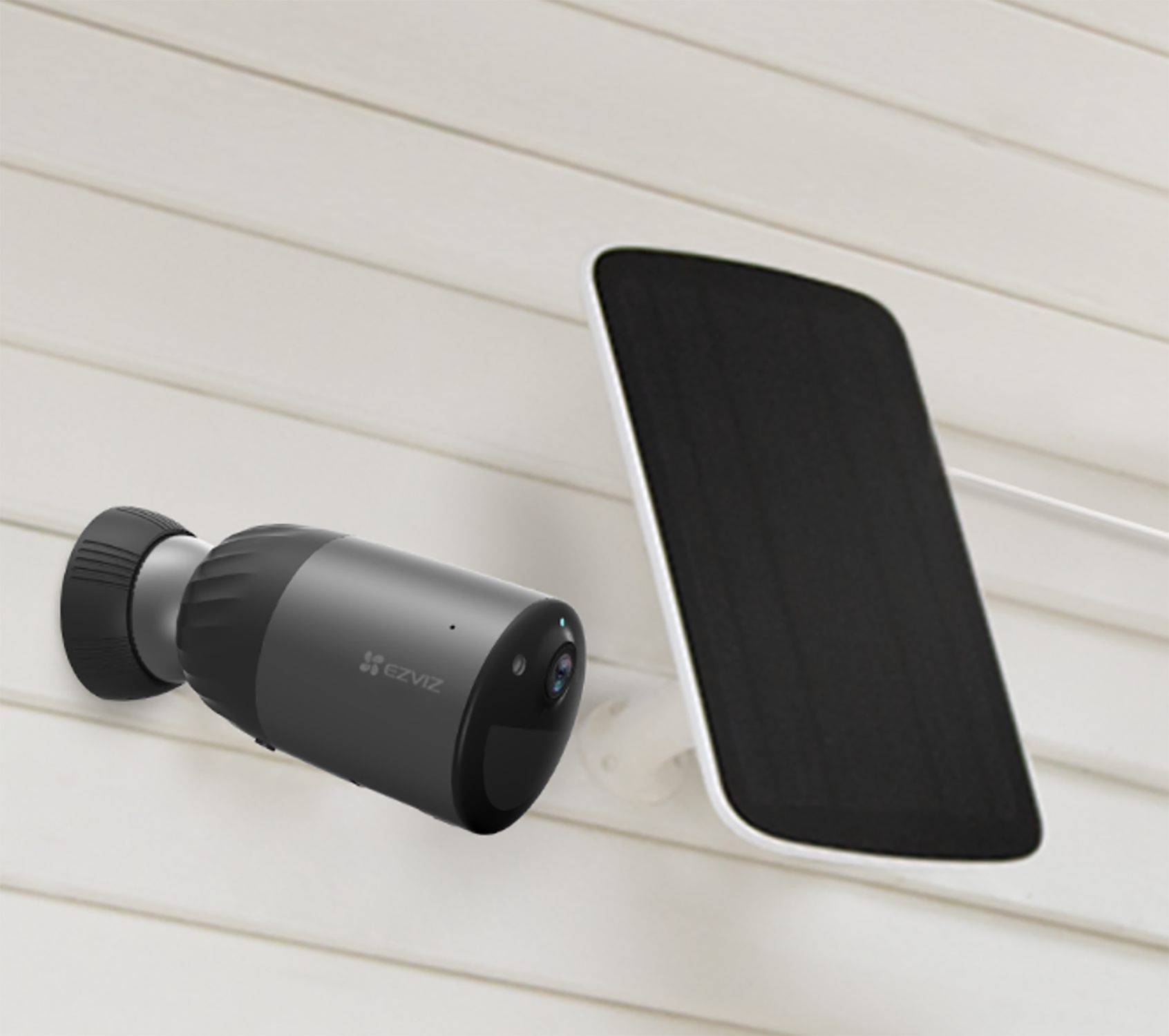 Czarno-szara kamera bezpieczeństwa z panelem słonecznym na białej ścianie.