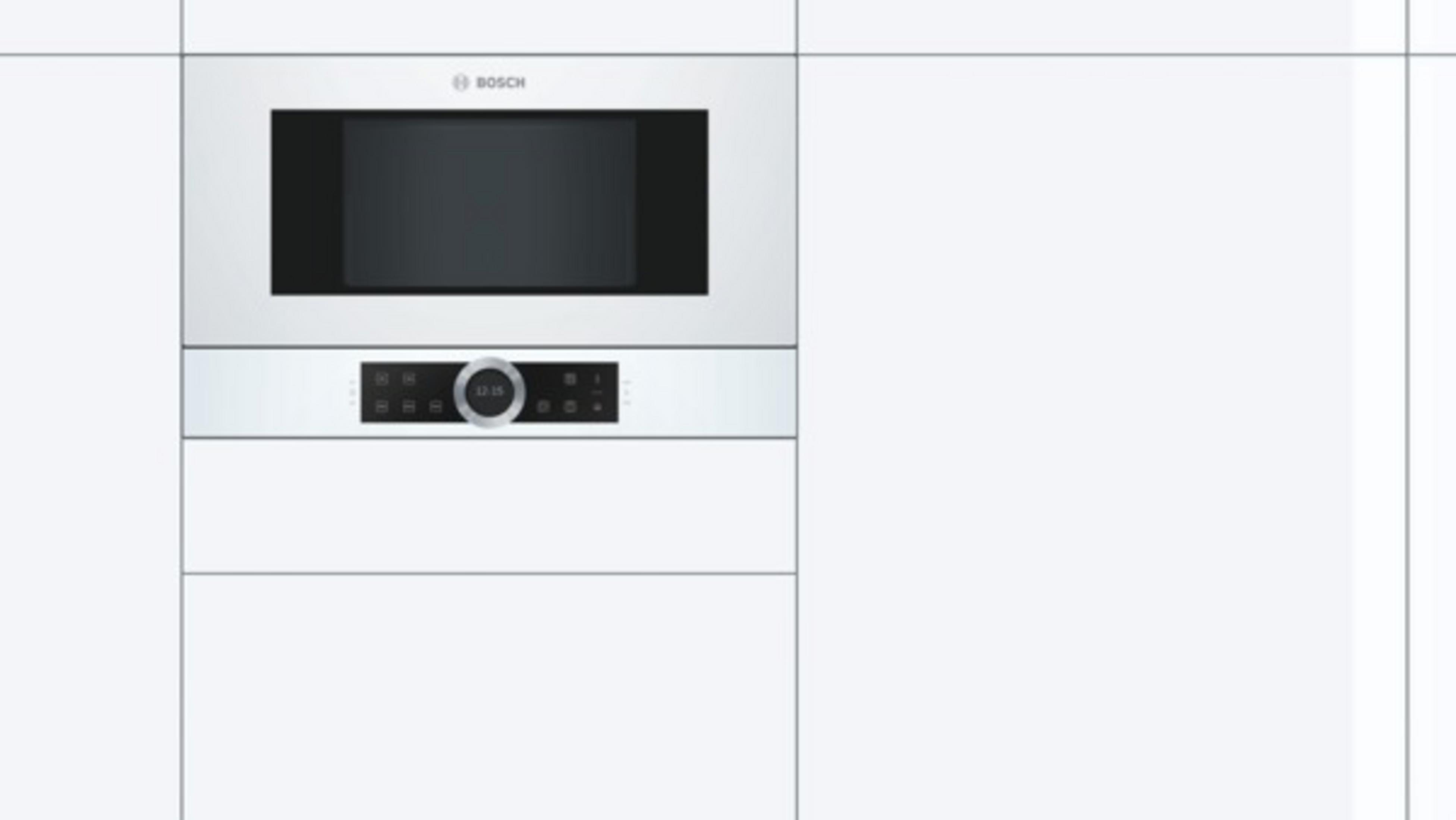 Horno microondas empotrado en un armario de cocina blanco.