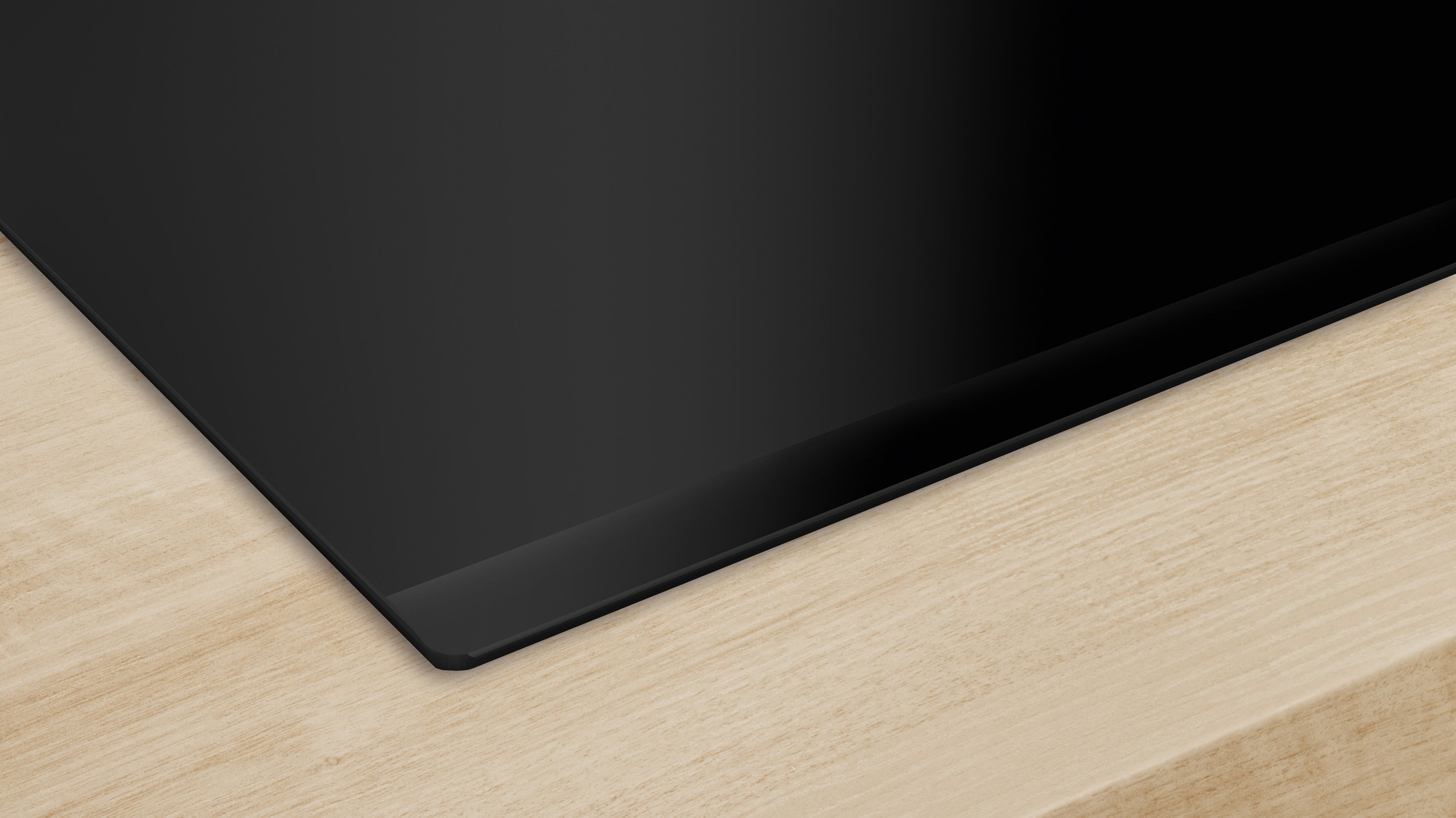 Czarna płyta kuchenna na drewnianej powierzchni. Zbliżenie na krawędź.