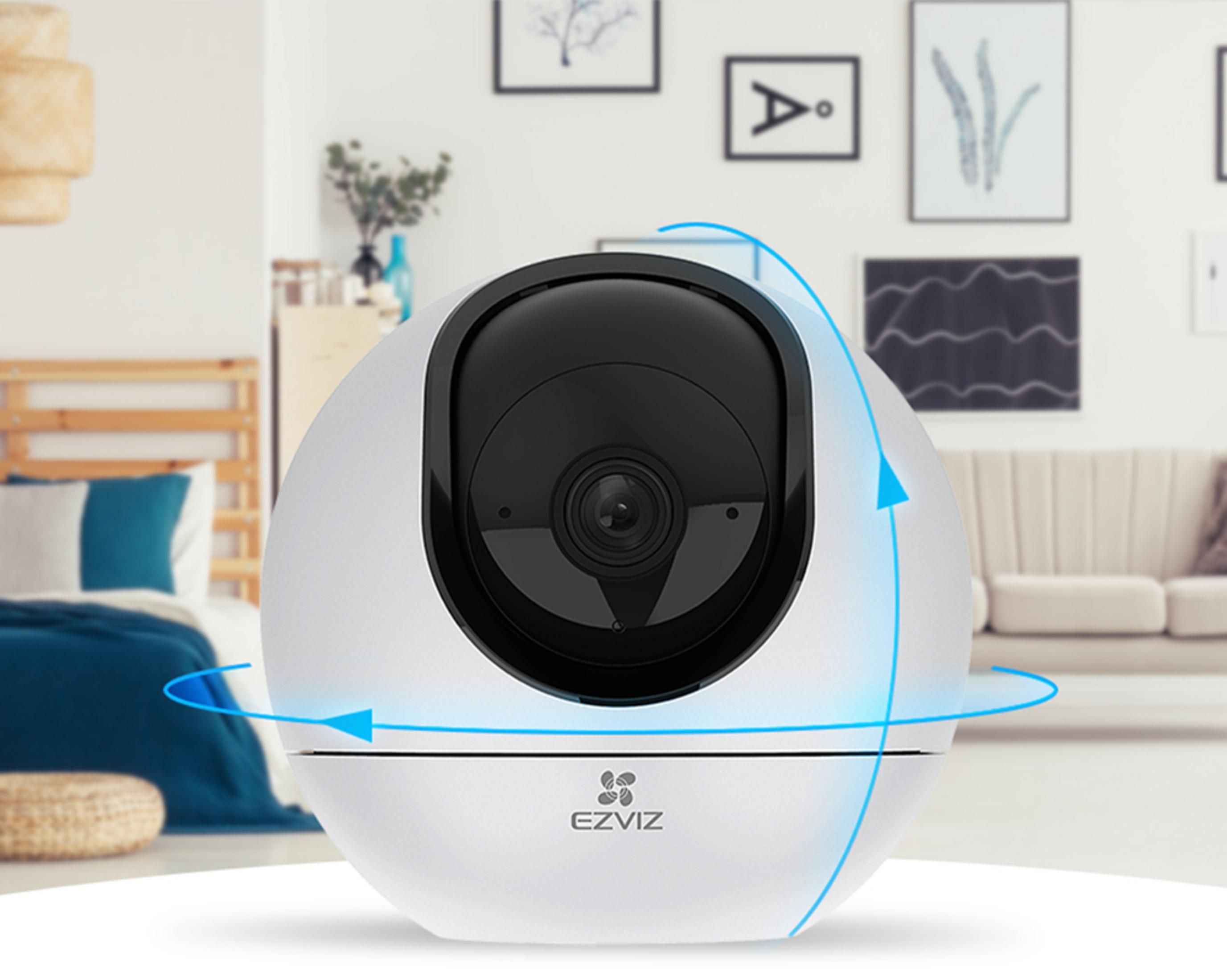 Una cámara EZVIZ blanca gira. La cámara está en un ambiente de sala de estar.