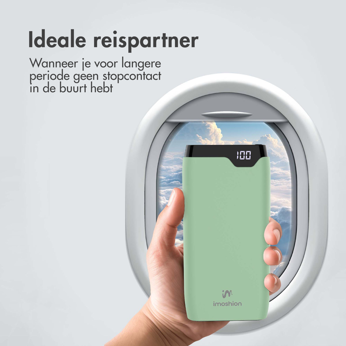 Une batterie externe verte tenue devant une fenêtre d'avion, affichant un écran numérique.