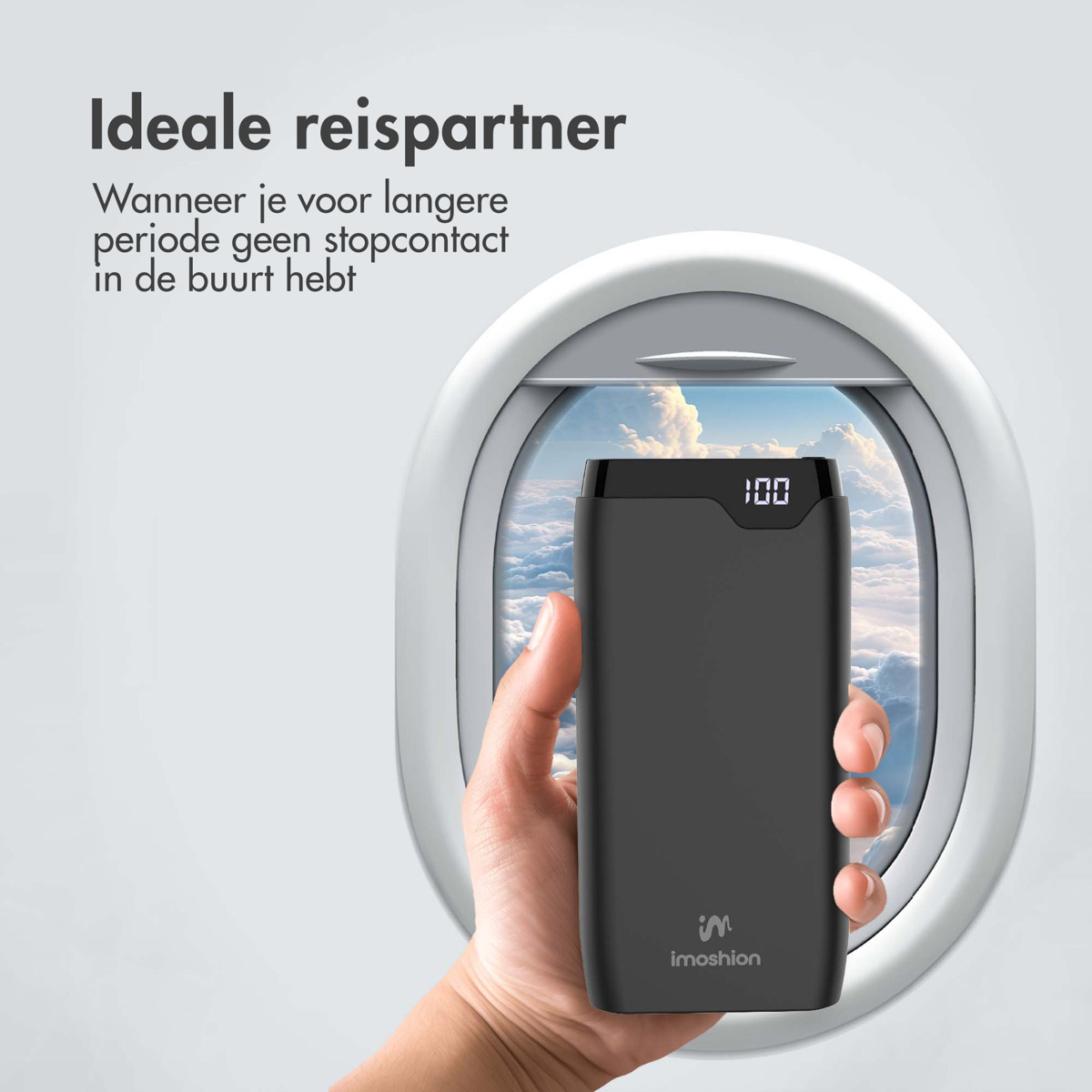 Hand hält eine schwarze Powerbank in der Nähe eines Flugzeugfensters. Niederländischer Text. Weißer Hintergrund.