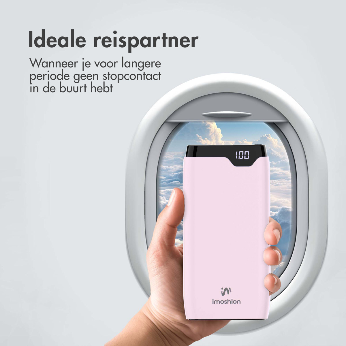 Une main tenant une batterie externe rose devant une fenêtre d'avion avec des nuages.