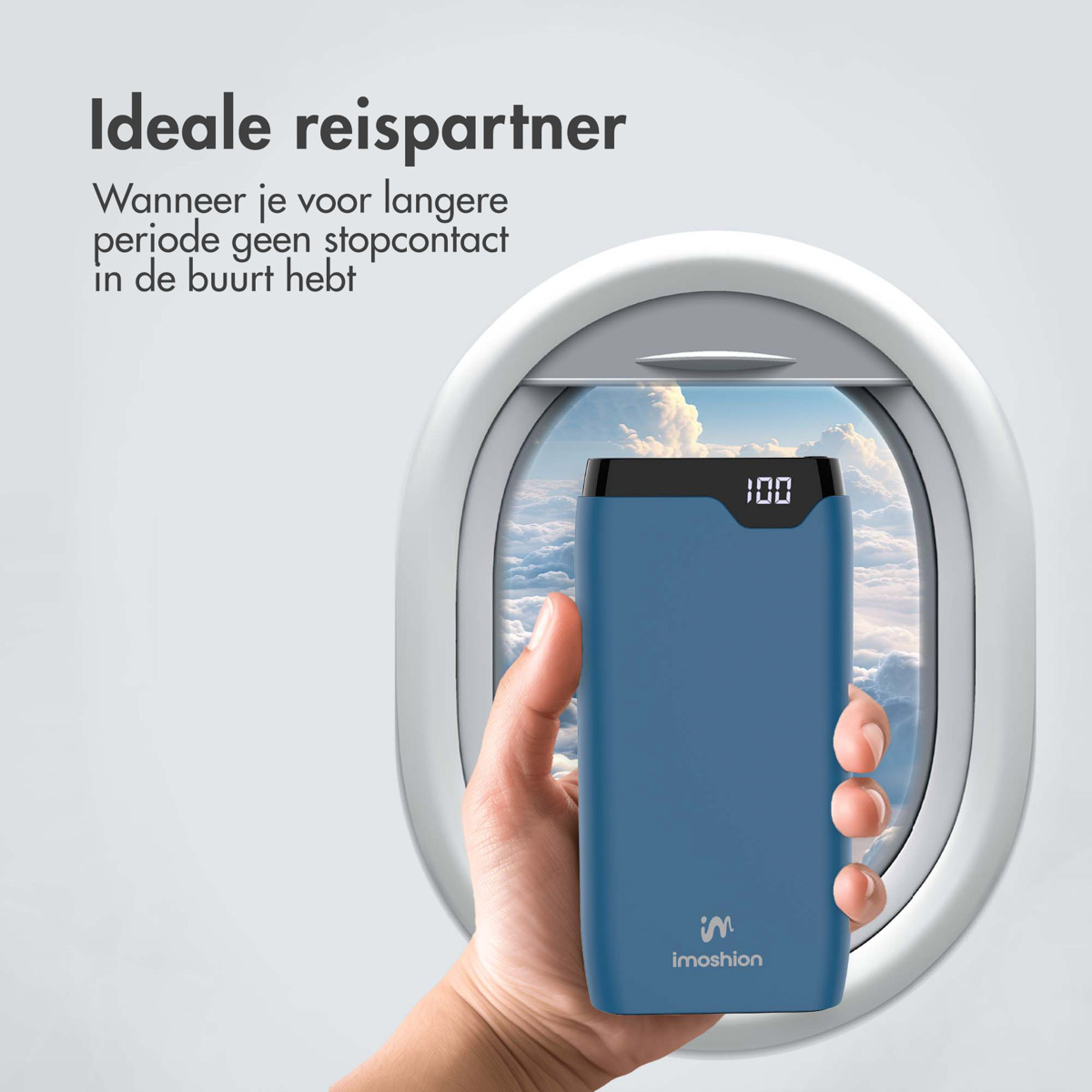 Eine Hand hält eine blaue Powerbank vor einem Flugzeugfenster. Die Powerbank zeigt 100% an. Das Fenster zeigt Wolken am Himmel.