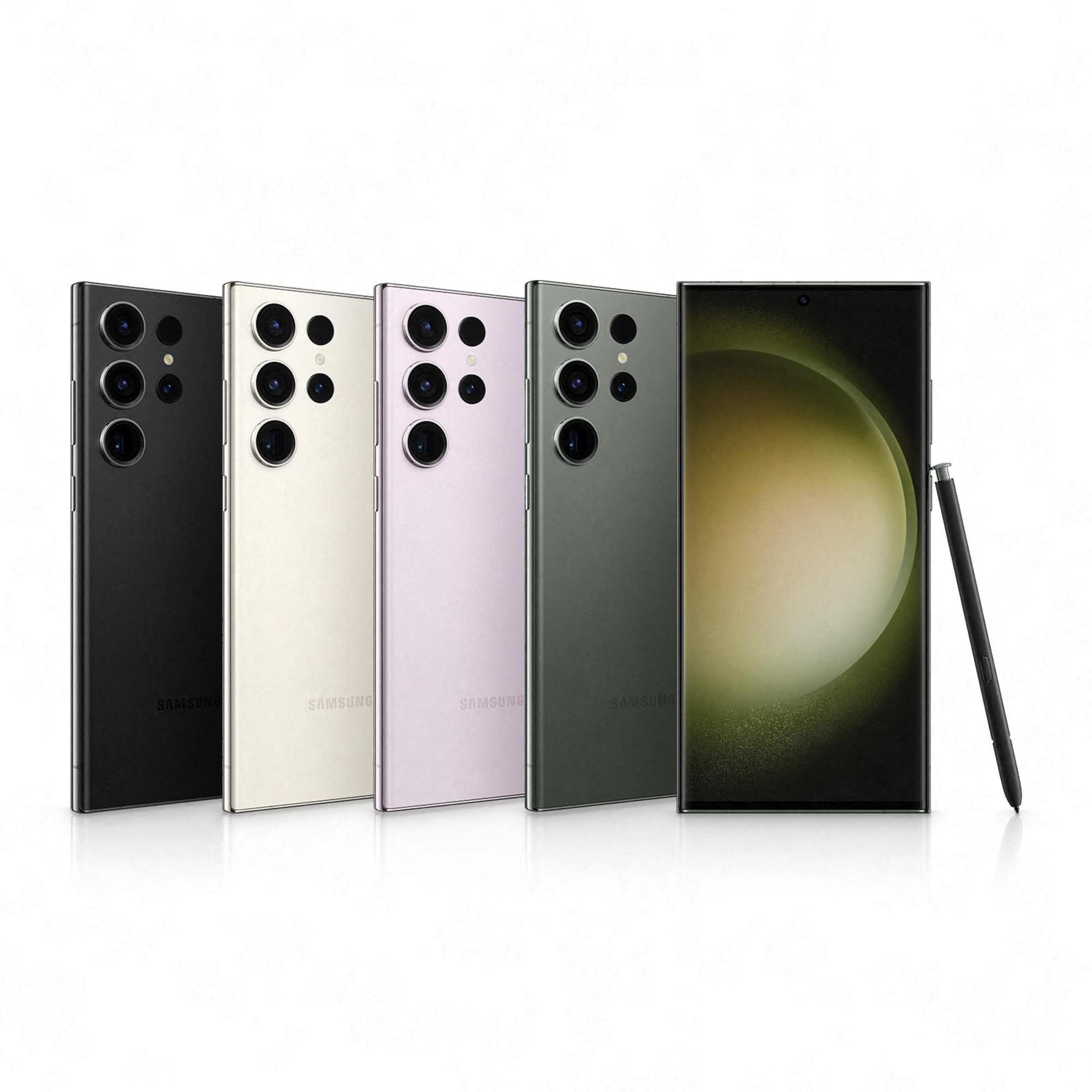 Kilka smartfonów w rzędzie, z czarnymi, kremowymi, różowymi i zielonymi tyłami, czarny długopis.