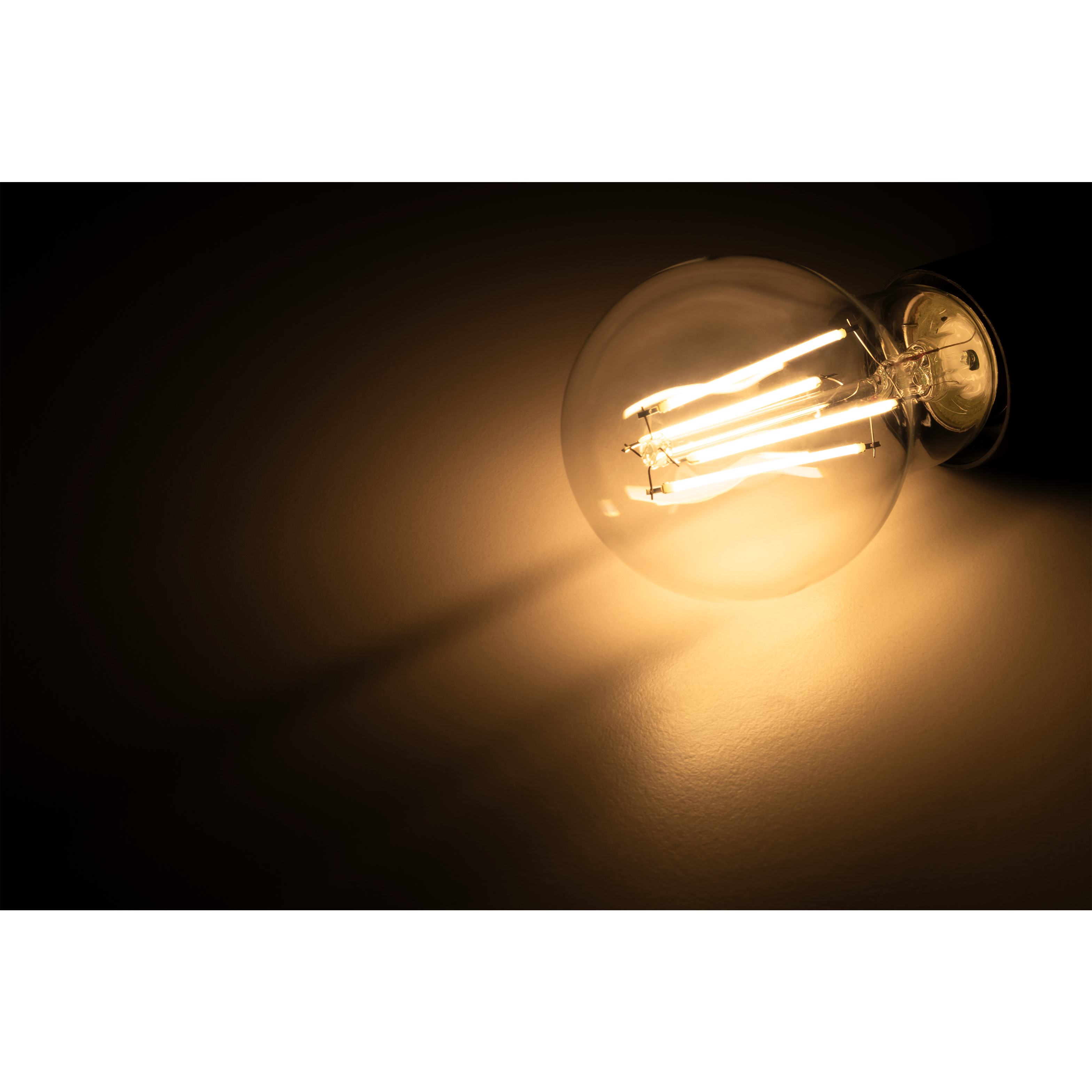 Eine leuchtende Glühbirne. Das Licht scheint auf eine hellfarbige Wand.